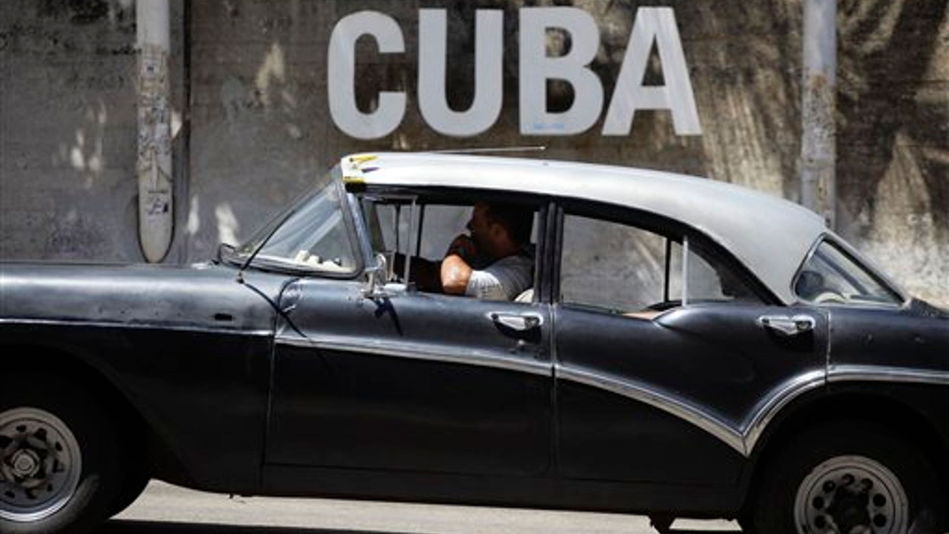 A man drives his taxi past a Cultural Center with the word "Cuba" on it, in Havana, Cuba, Tuesday, April 14, 2015.