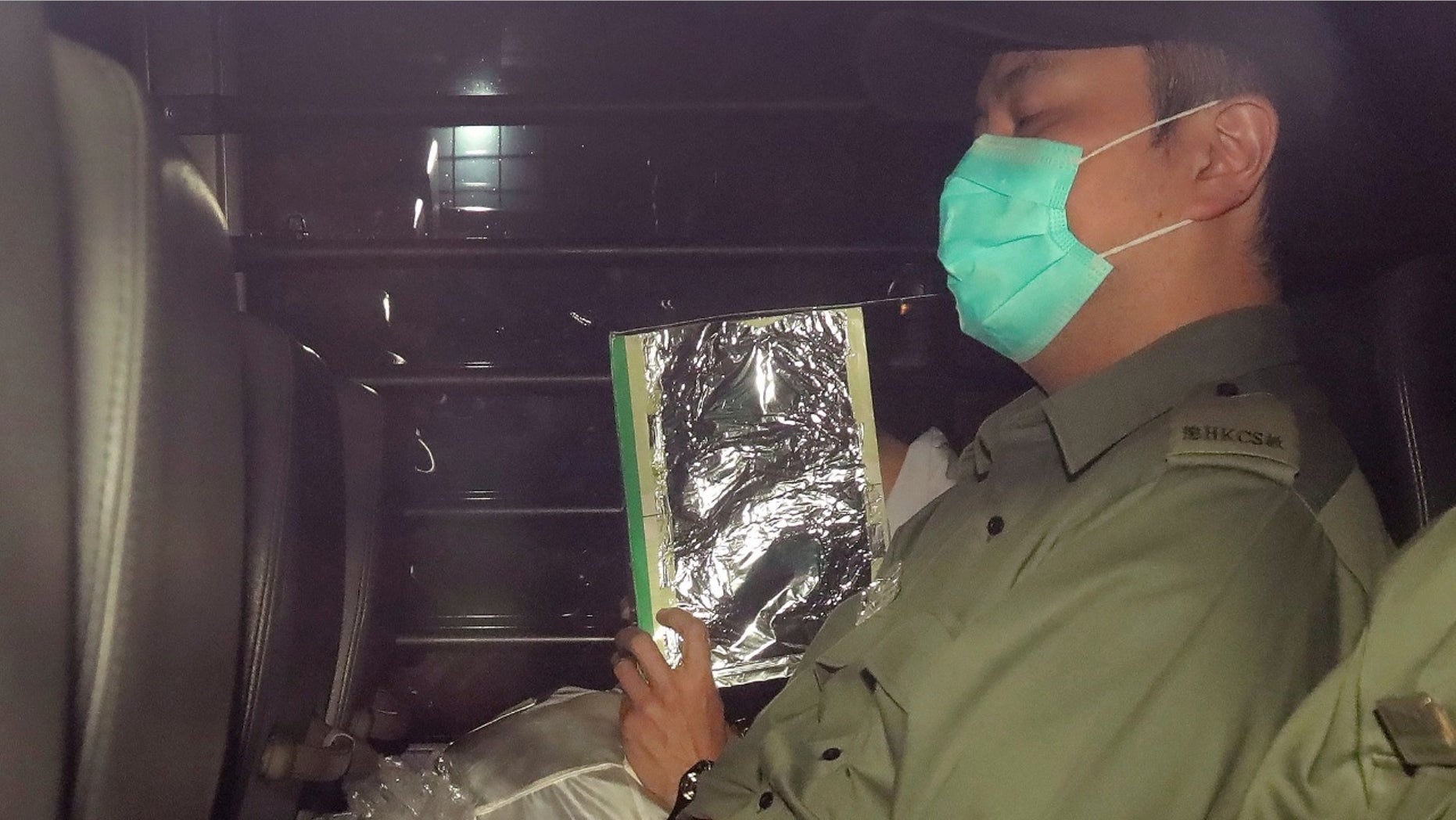 Malaysian citizen Khaw Kim Sun, 53, center, covered face, is escorted in a prison bus leaving the court after being sentenced to life in prison in Hong Kong.