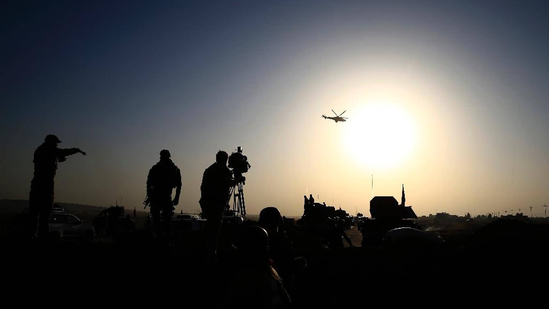 An Iraqi military helicopter flies over the frontline near Bartella, Iraq on Thursday, Oct. 20, 2016. Iraqi special forces charged into the Mosul battle Thursday with a pre-dawn advance on the nearby town held by the Islamic State group, a key part of a multi-pronged assault on eastern approaches to the besieged city. (AP Photo/Bram Janssen)