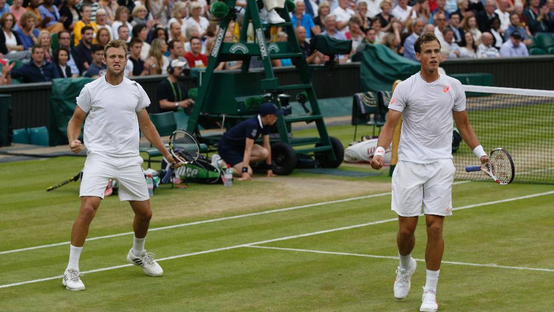 Vasek Pospisil of Canada, right, and Jack Sock of the U.S celebrate a point during the men's doubles final against Bob Bryan and Mike Bryan of the U.S at the All England Lawn Tennis Championships in Wimbledon, London, Saturday, July 5, 2014. (AP Photo/Pavel Golovkin)