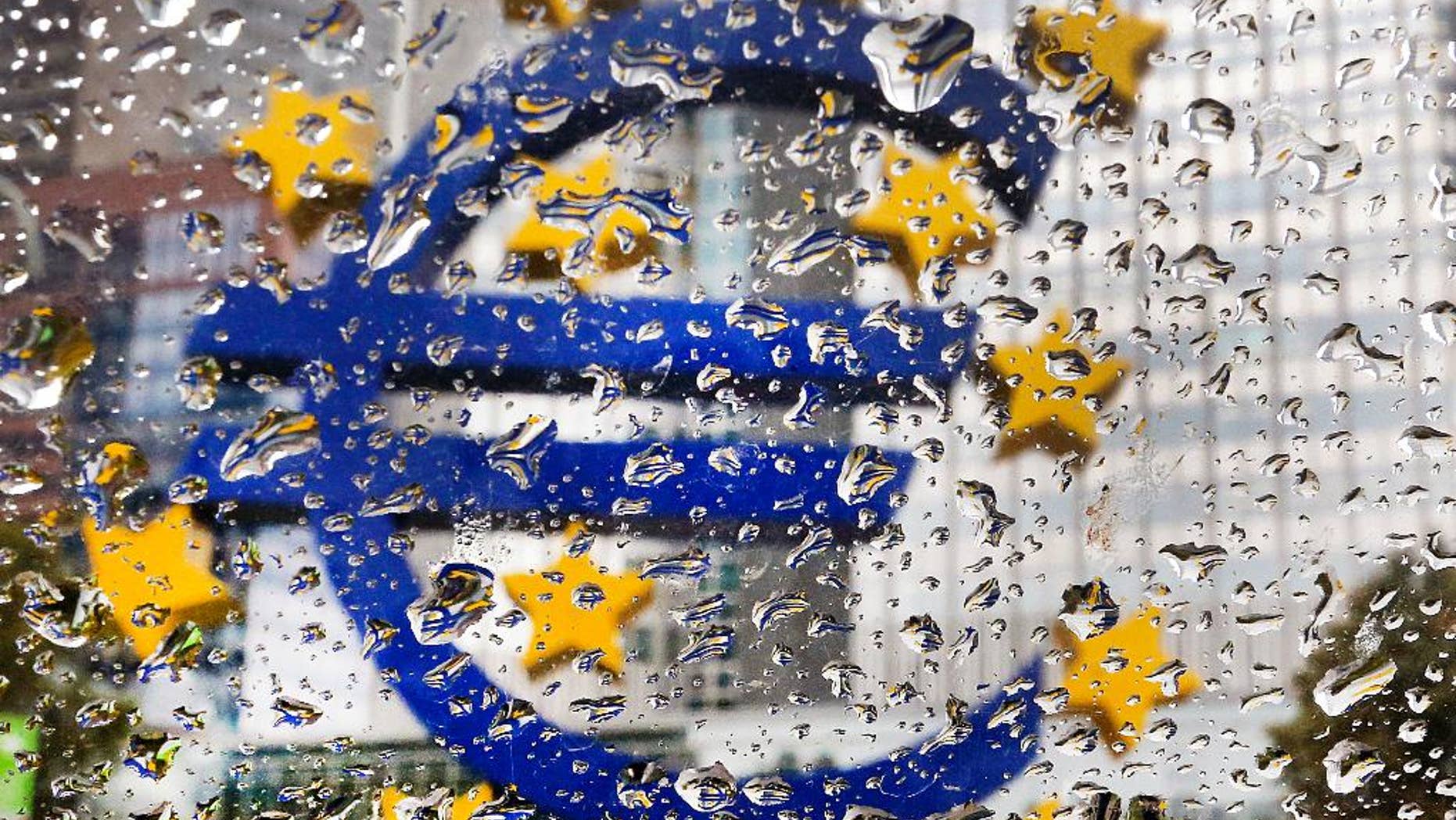 The Euro sculpture in front of the old European Central Bank is photographed behind rain drops on a window in Frankfurt, Germany, Tuesday, Oct. 18, 2016. The governing council of the ECB will meet on Thursday. (AP Photo/Michael Probst)