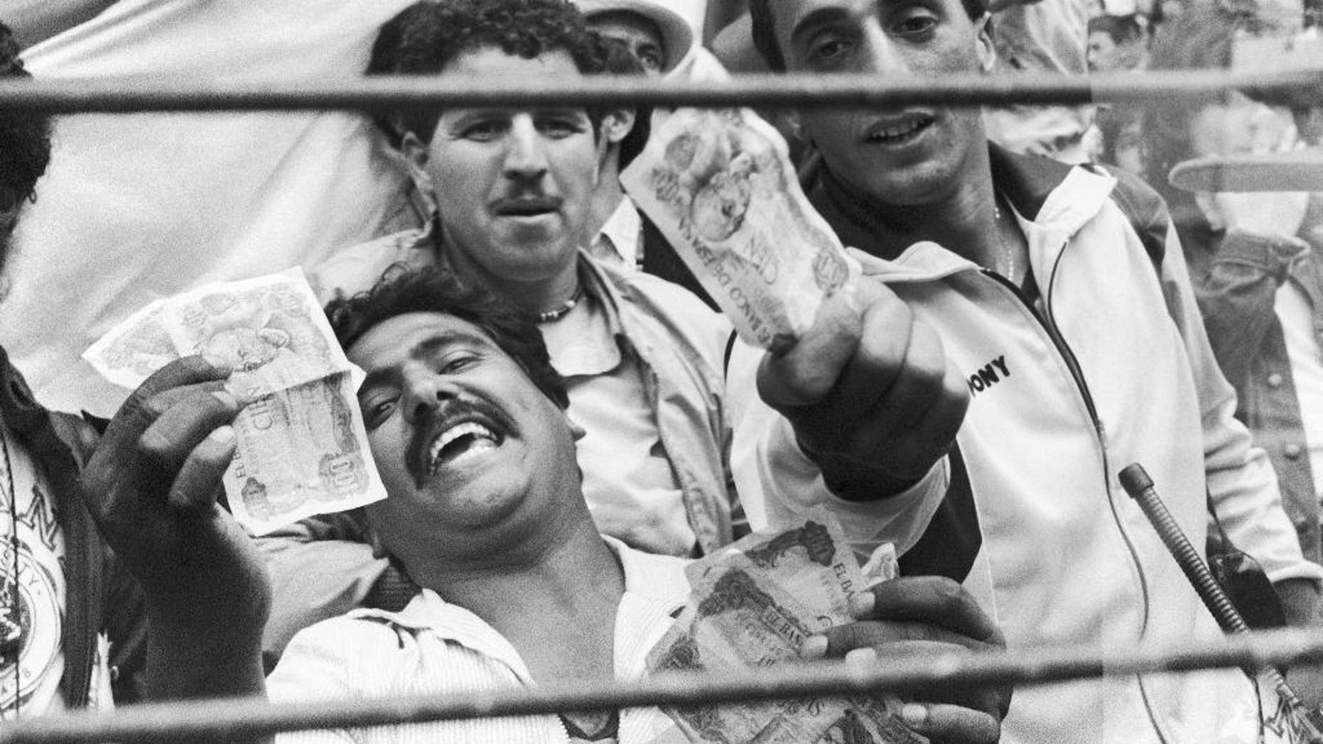 FILE - In this June 25, 1982 file photo, Algerian soccer supporters show money to photographers, in Gijon, Spain, after the World Cup soccer match between West Germany and Austria. On this day: West Germany beat Austria 1-0, a result that meant both teams progressed to the next round at Algeria's expense. After West Germany took an early lead, the game ran its bland course to conclusion to the ire of the watching Algerians. (AP Photo/File)