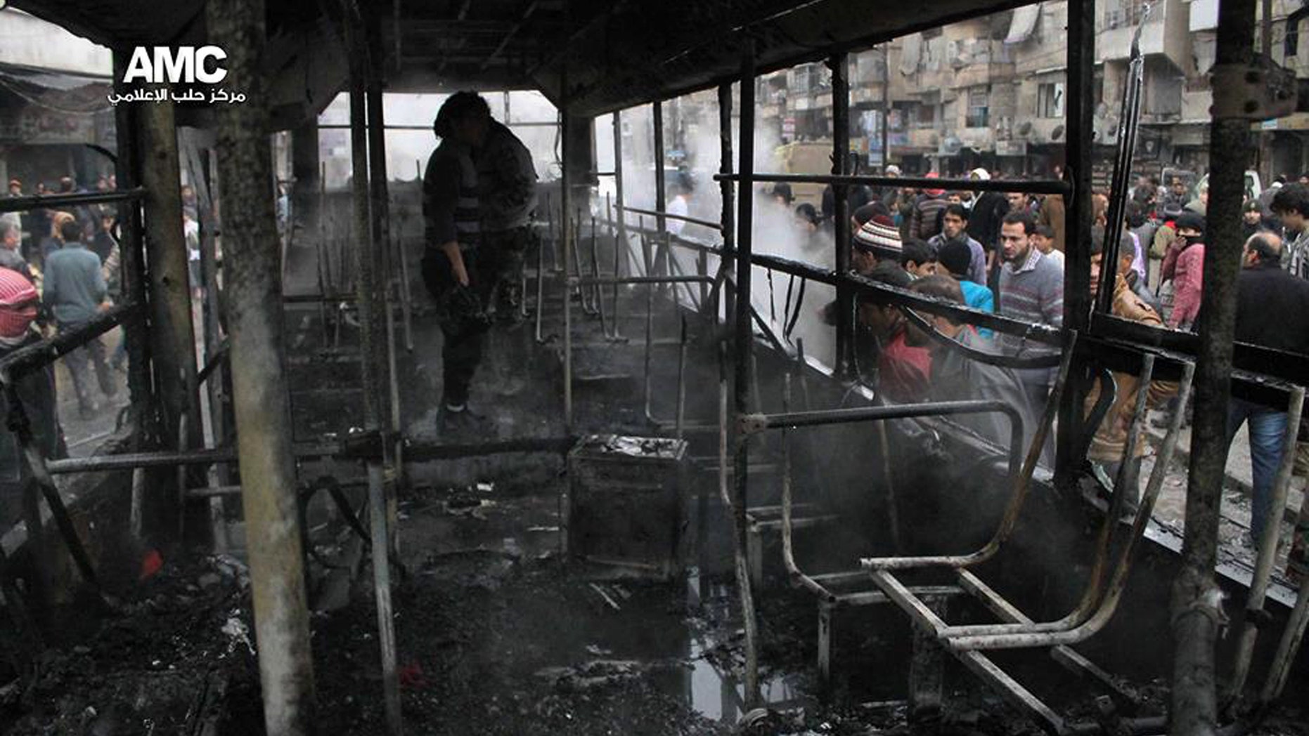 This citizen journalism image provided by Aleppo Media Center AMC which has been authenticated based on its contents and other AP reporting, shows Syrians inspecting a burnt bus after a missile fired by Syrian government aircraft hit the vehicle in the rebel-held neighborhood of al-Bab in Aleppo, Syria, Tuesday, Dec. 31, 2013. The bus was full of people when it was struck, setting it on fire and killing several people, activists said. (AP Photo/Aleppo Media Center AMC)