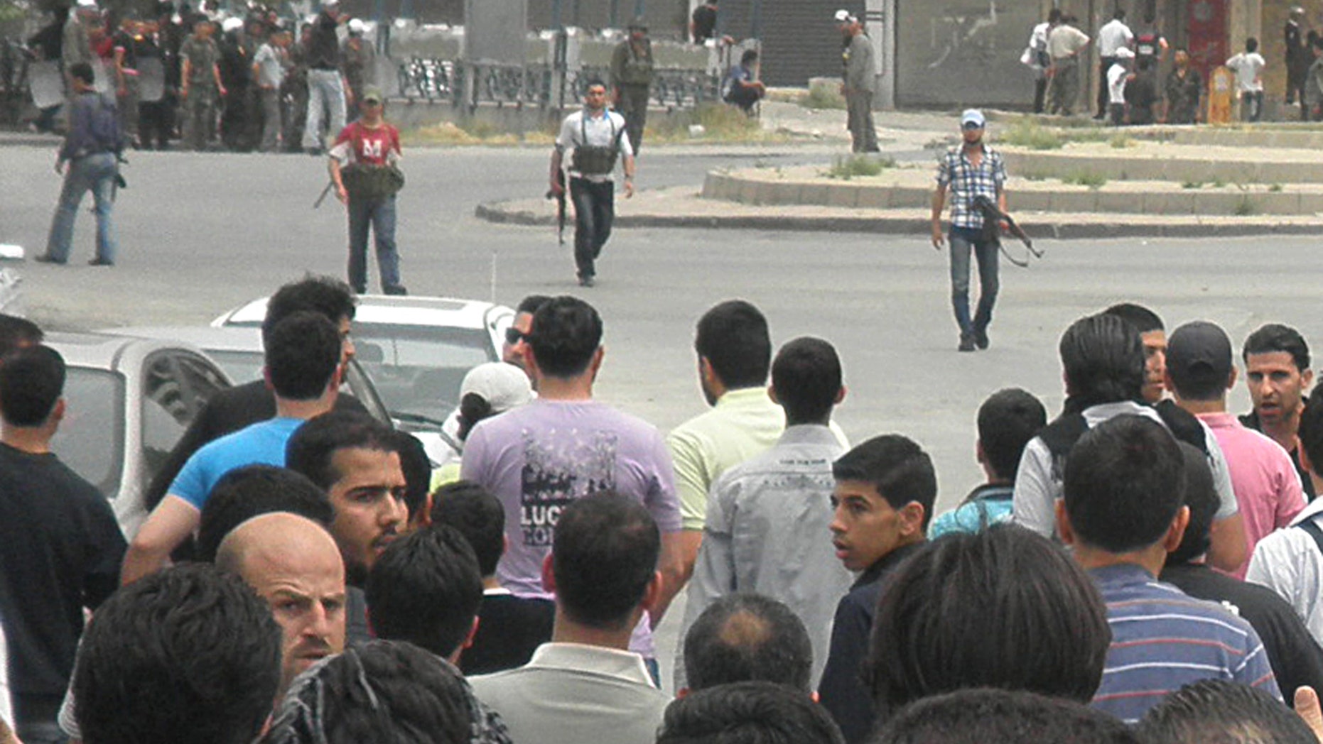 April 30, 2012: In this file photo, Syrian security forces, background, hold their machine guns and surround anti-Syrian regime mourners, foreground, during the funeral procession of the activist Nour al-Zahraa, 23, who was shot by the Syrian security forces on Sunday, in Kfar Suseh area, in Damascus, Syria.