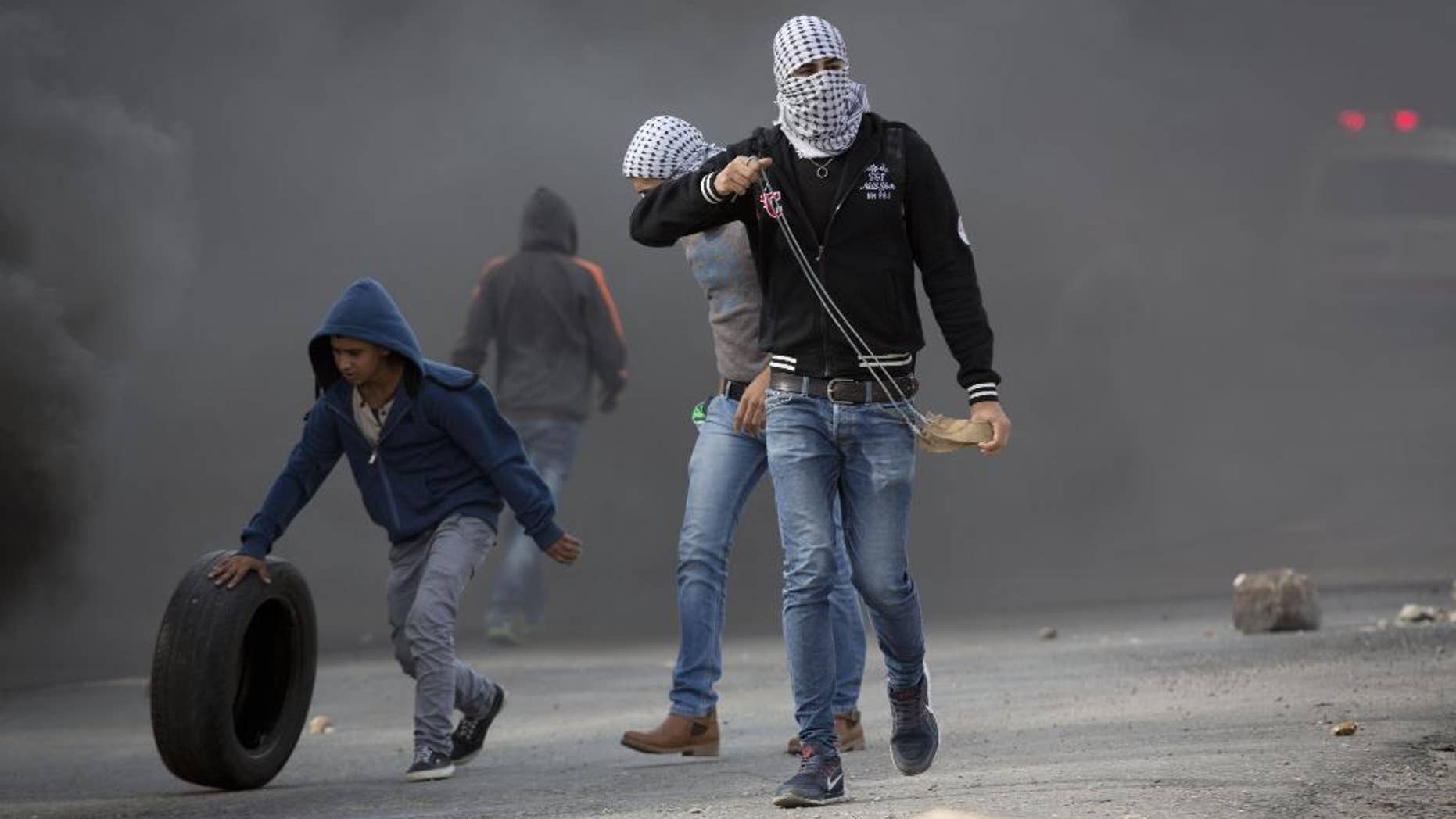 Palestinian protesters prepare to throw stones at Israeli troops Tuesday.