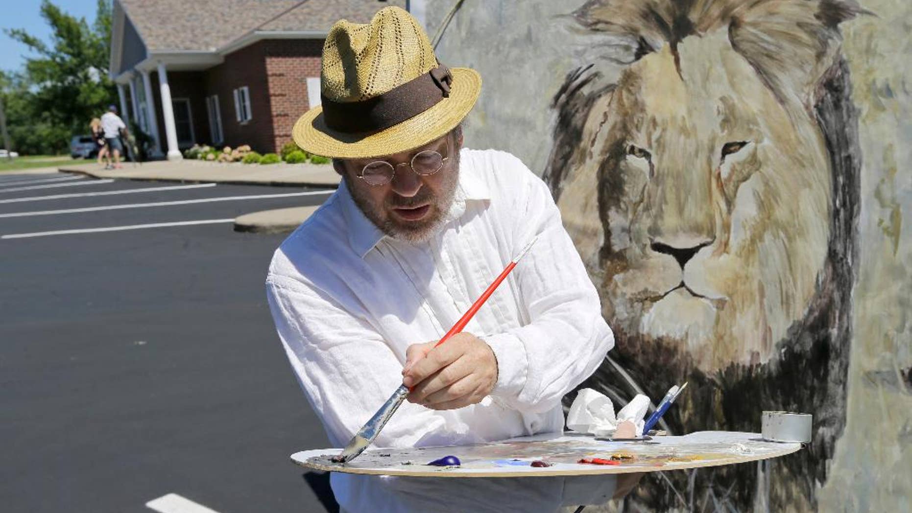 FILE - In this July 29, 2015, file photo, artist Mark Balma paints a mural of Cecil, a well-known lion killed by Minnesota dentist Walter Palmer during a guided bow hunting trip in Zimbabwe, as part of a silent protest outside Palmer's office in Bloomington, Minn. Palmer participated in an interview Sunday, Sept. 6, in which he disputed some accounts of the hunt, expressed agitation at the animosity directed at those close to him and said he would be back at work within days. (AP Photo/Ann Heisenfelt, File)