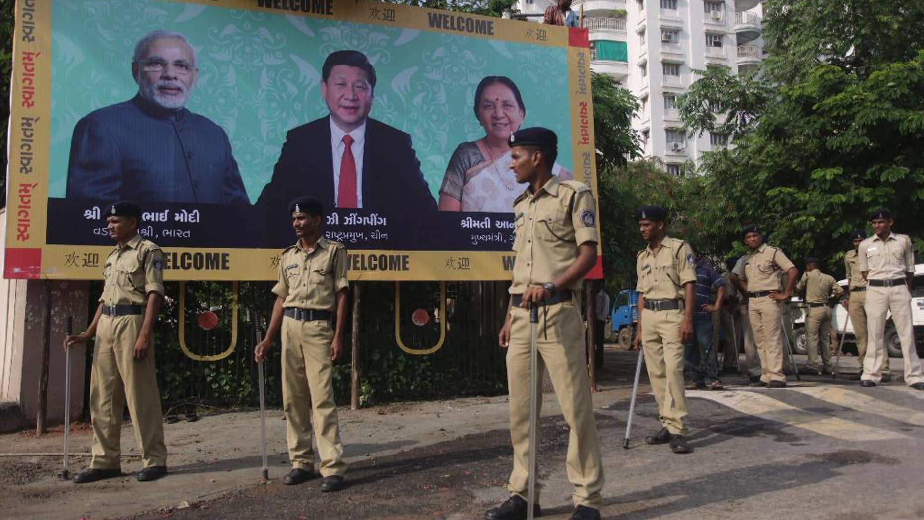 Indian policemen stand next to a welcome hoarding being erected ahead of an anticipated visit by Chinese President Xi Jinping as they review security arrangements in Ahmadabad, India, Monday, Sept. 15, 2014. Jinping is expected to arrive here Wednesday on his three-day visit to India. The hoarding also features Indian Prime Minister Narendra Modi, left and Gujarat state Chief Minister Anandiben Patel, right. (AP Photo/Ajit Solanki)