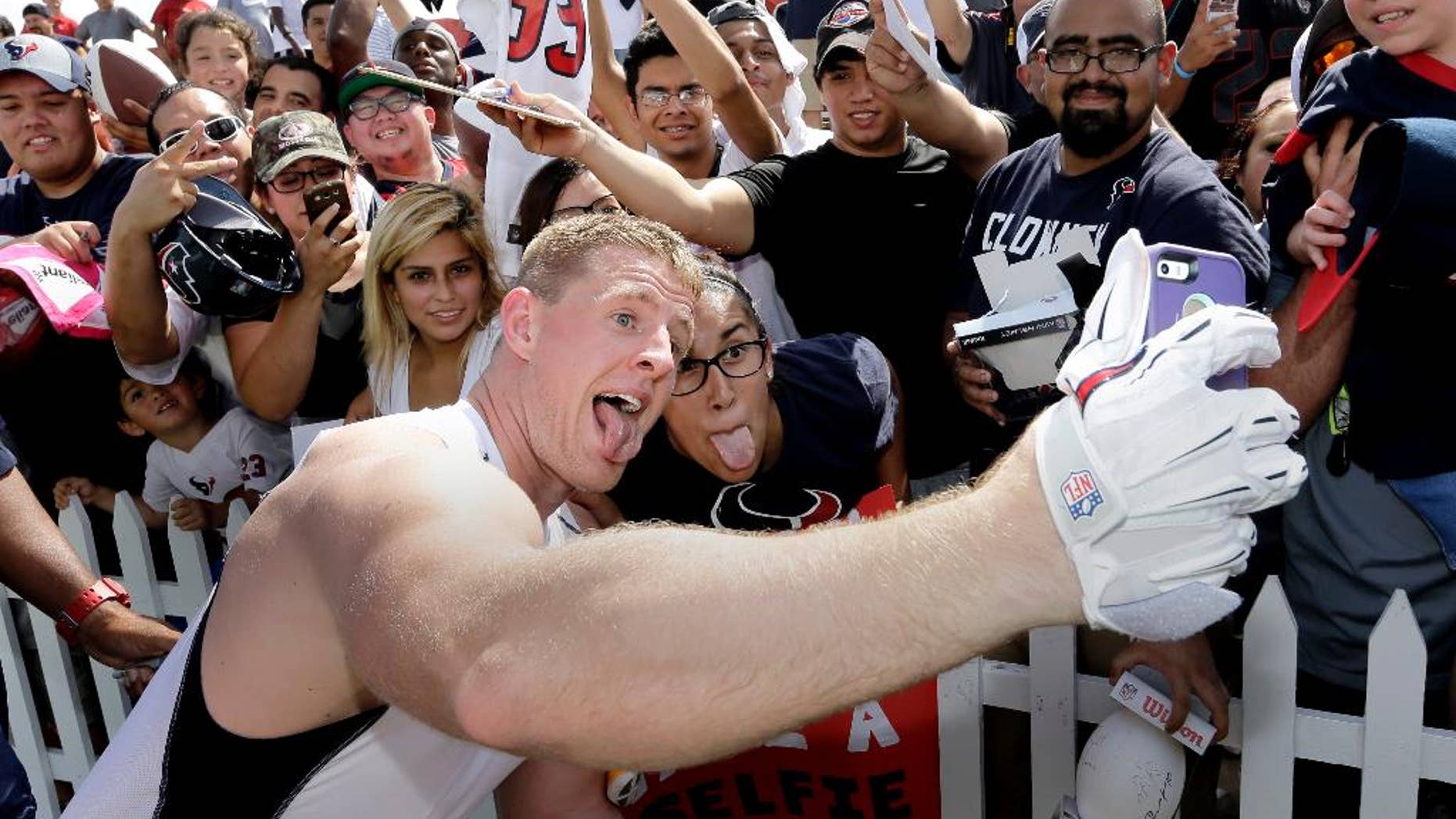 Houston Texans defensive end J.J. Watt, left, takes a selfie with Nina Munduia after an NFL football training camp practice on Saturday, July 26, 2014, in Houston. (AP Photo/David J. Phillip)