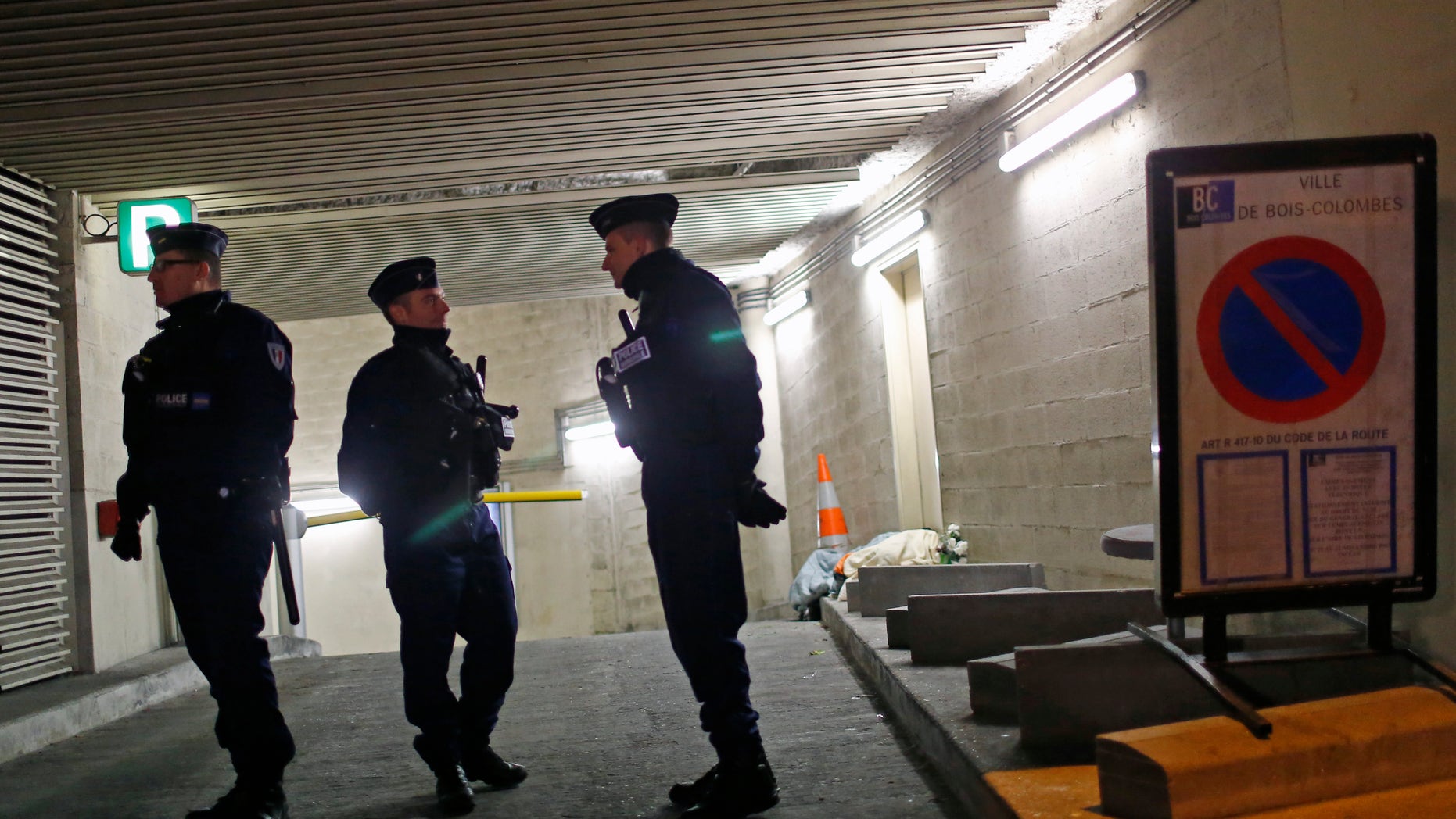 Nov. 21, 2013: Police officers stand guard in front of the entrance of a parking lot where a man, believed to be the suspect in a Paris newspaper office shooting, was detained, in Bois Colombes, outside Paris.