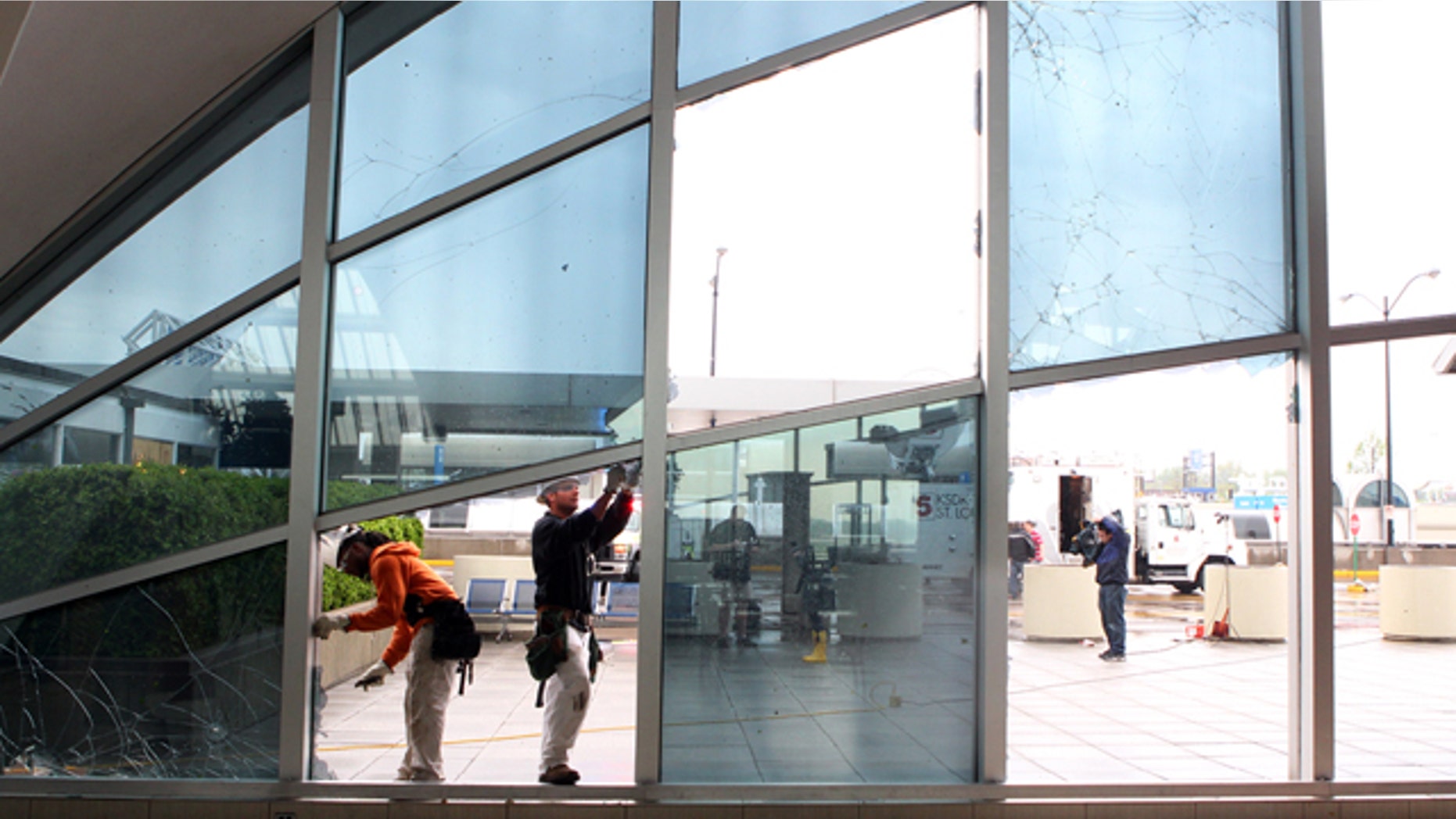 April 23: From left to right, Shaun Jones and Jacob Caldwell of BAM Contracting in St. Louis, work to repair damage to windows in the main terminal of St. Louis' Lambert International Airport
