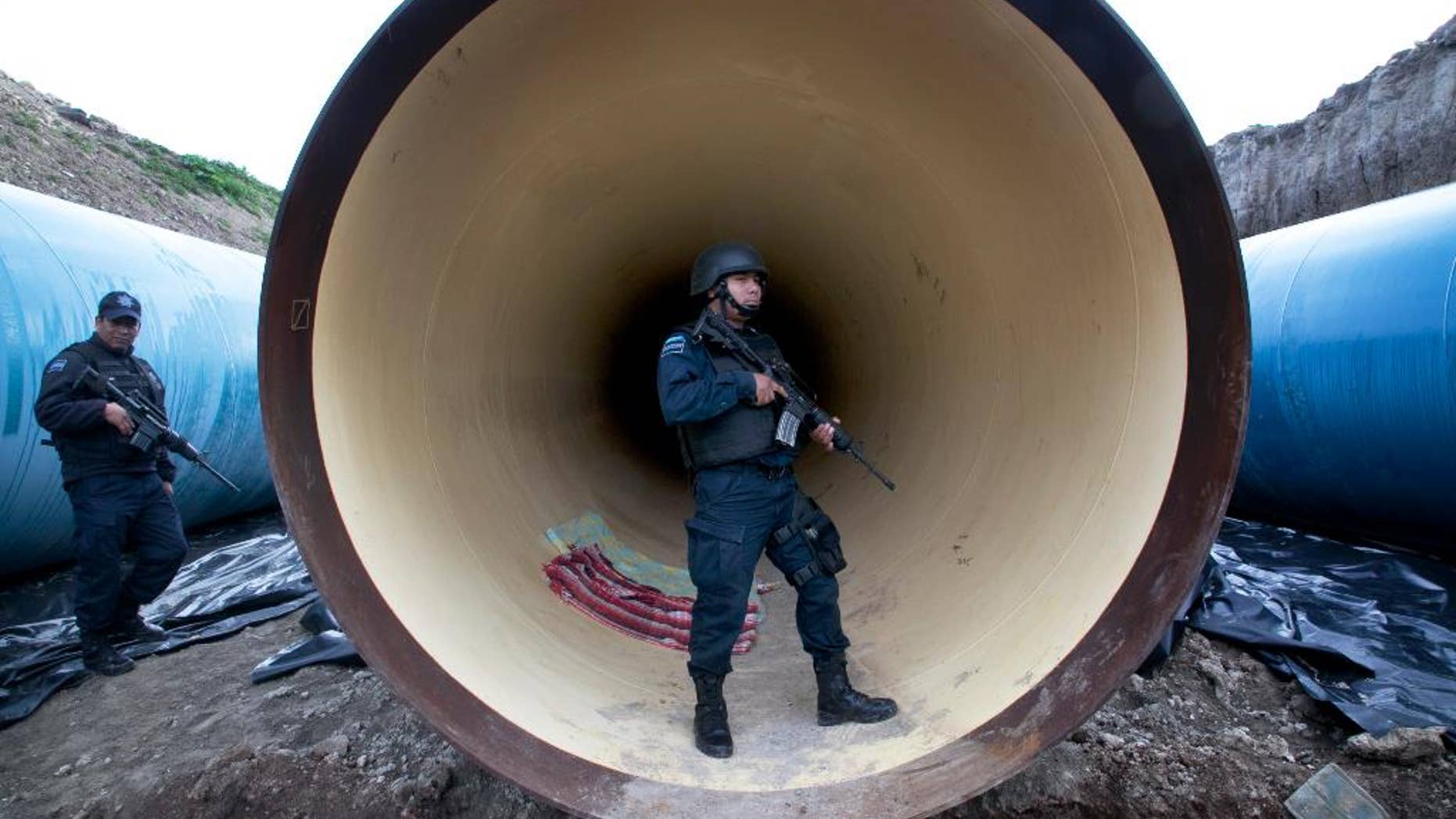 FILE - In this Sunday, July 12, 2015, file photo, Mexican Federal Police guard a drainage pipe outside of the Altiplano maximum security prison in Almoloya, west of Mexico City. Mexican officials said Wednesday, Oct. 21, 2015, that they have captured six people who helped the notorious drug cartel boss break out of prison in July. The suspects include a man considered the mastermind of the escape, the capo’s brother-in-law and an airplane pilot. (AP Photo/Marco Ugarte, File)