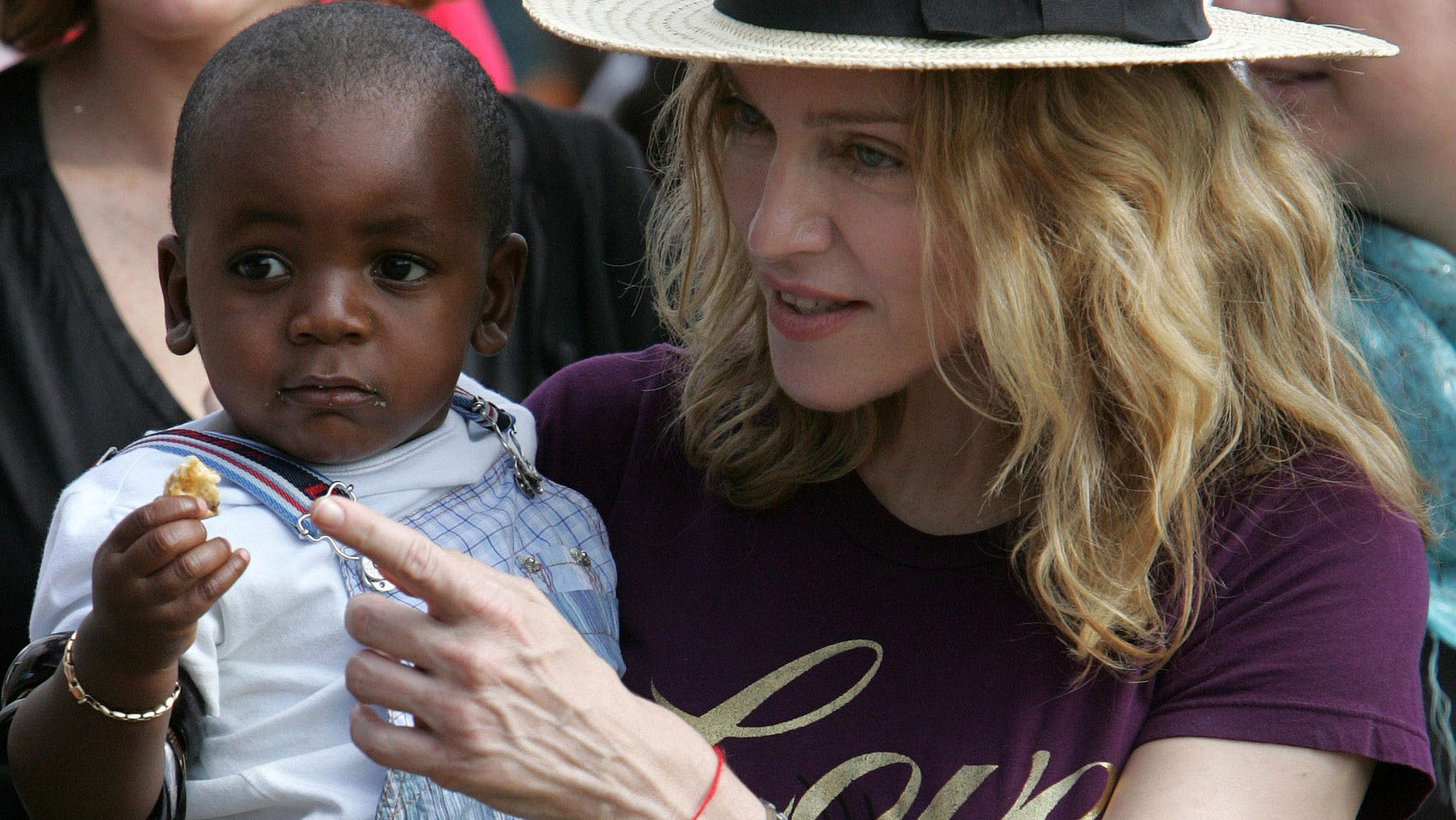 FILE- In this April 19, 2007 file photo, U.S. singer Madonna carries her Malawian adopted son David Banda at Consol Homes, a day care center that she is funding in the village of Masekese, Malawi. Madonna, who has adopted two children from Malawi, arrived back in the country at 9am local time, Sunday, April 1, 2013, according to Kamuzu International Airport (KIA) immigration officials in the capital, Lilongwe. (AP Photo/Karel Prinsloo, file)