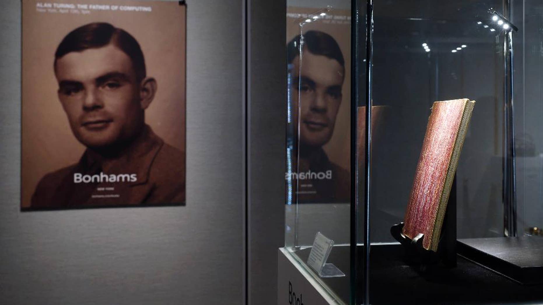 FILE - In this Thursday, March 19, 2015 file photo, a notebook of British mathematician Alan Turing is displayed in front of his portrait during an auction preview in Hong Kong. Thousands of men convicted under now-abolished anti-homosexuality laws in Britain have been pardoned posthumously under a law passed on Tuesday, Jan. 31, 2017 and many more still alive can now apply to have their criminal convictions wiped out. Calls for a general pardon have noted the 1954 suicide of World War II codebreaking hero Alan Turing after his conviction for "gross indecency." After he received a posthumous royal pardon in 2013, pressure for pardons intensified. (AP Photo/Kin Cheung, file)