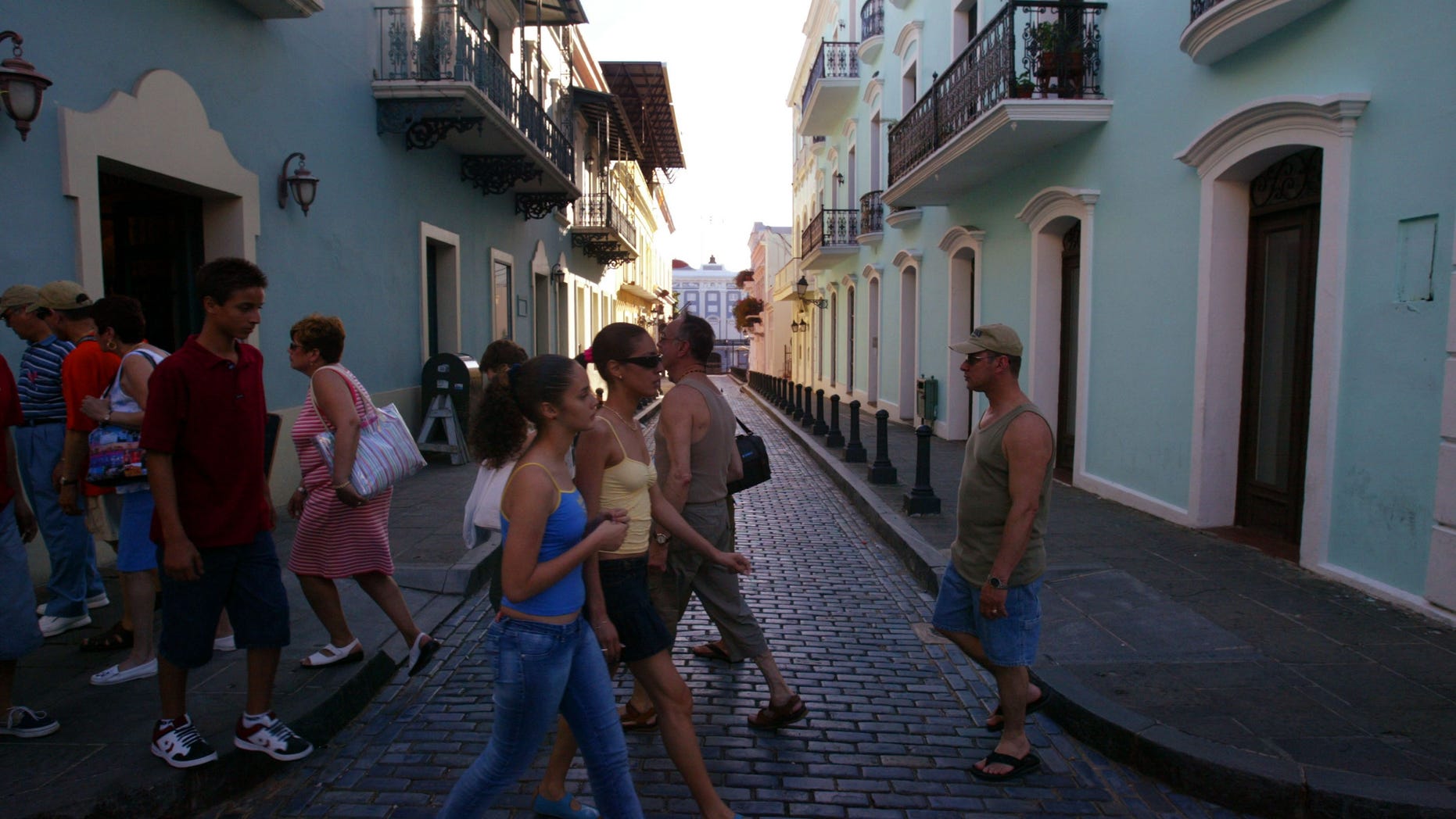 SAN JUAN, PUERTO RICO- APRIL 25: Visitors walk past colorful homes that line the cobblestoned streets April 25, 2004 in Old San Juan, the original capital city of San Juan, Puerto Rico. The old city is a historic district of seven square blocks made up of ancient buildings and colonial homes, massive stone walls and vast fortifications, sunny parks and cobblestoned streets. (Photo by Joe Raedle/Getty Images)
