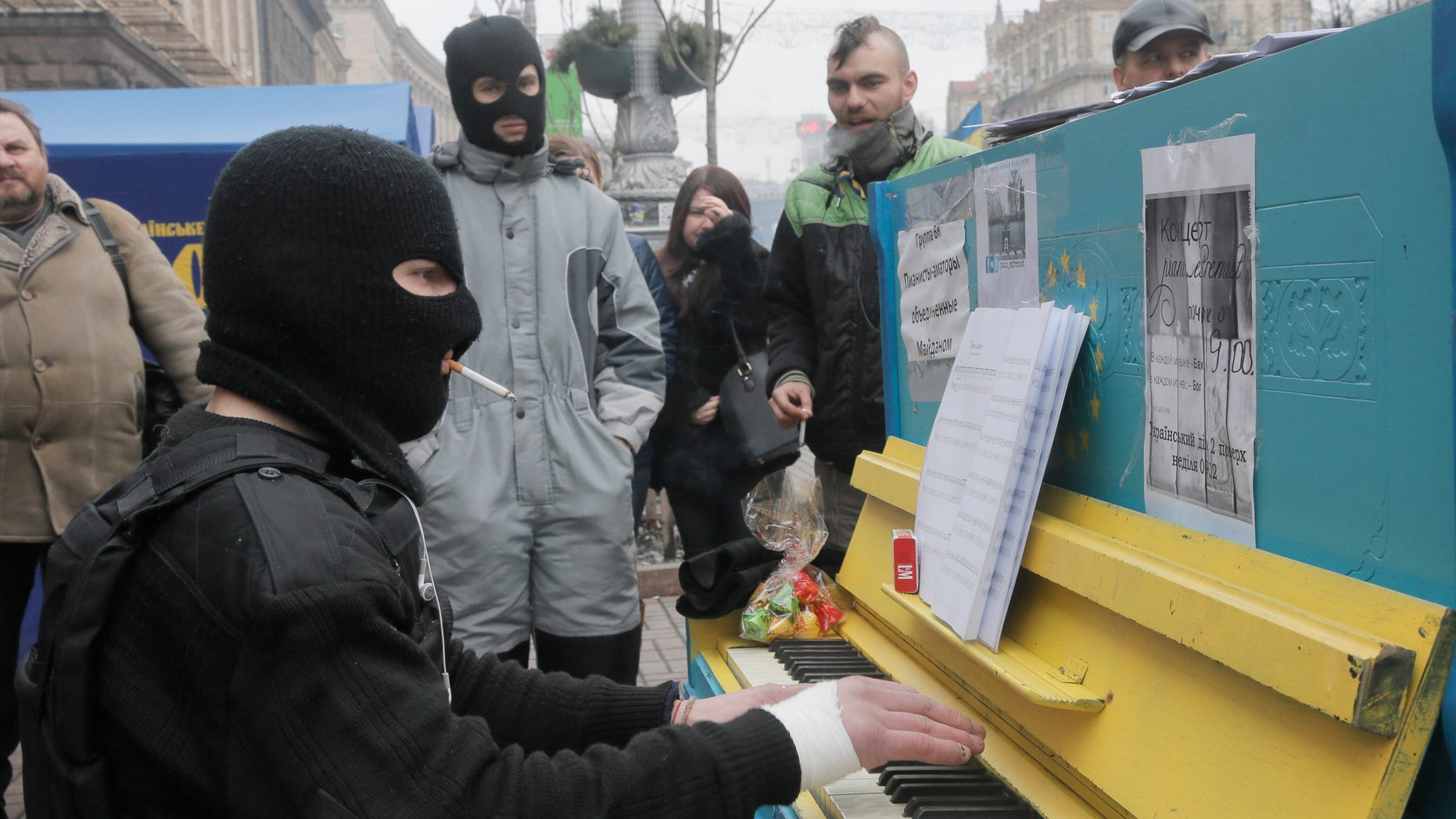 A protester in a balaclava and a flak jacket plays the piano in Kiev's Independence Square, the epicenter of the country's current unrest, Ukraine, Friday, Feb. 14, 2014. A Ukrainian opposition group says that all the protesters detained during nearly three months of opposition demonstrations have been released under an amnesty law. (AP Photo/Efrem Lukatsky)
