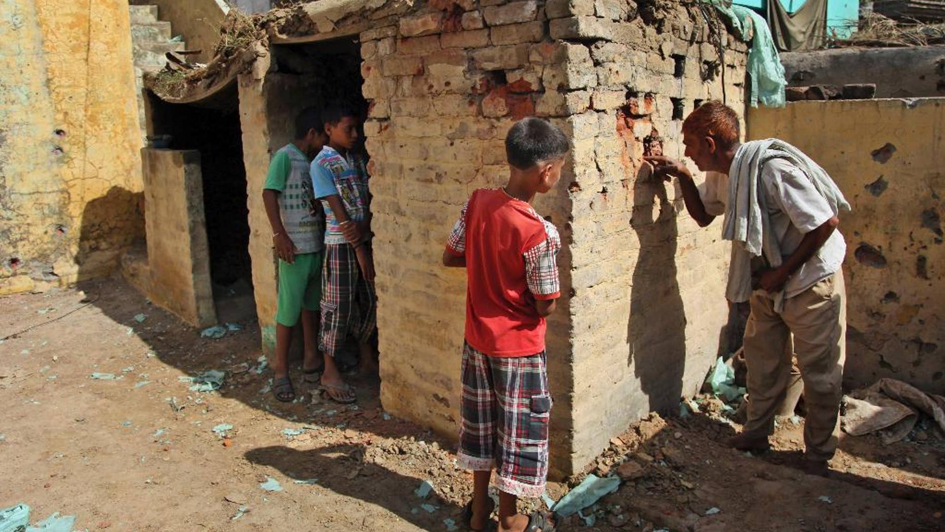 An Indian village man looks at one of the houses damaged in firing between India and Pakistan at the border area of Treava village in Arnia sector, in Jammu, India, Saturday, Oct. 11, 2014. Exchanges of fire are common along the tense and heavily guarded frontier, but this week's flare-up, which left more than 20 people dead, is the most serious violation yet of a 2003 cease-fire agreement. (AP Photo/Channi Anand)