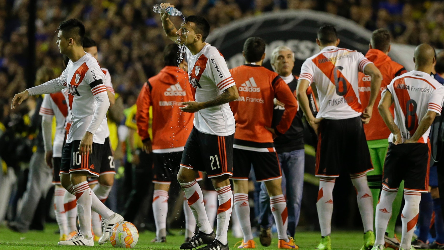 Argentina's River Plate players walk on the field as Leonel Vangioni rinses his face after pepper spray was thrown at them from the stands before the start of the first half of the Copa Libertadores round of sixteen soccer match against Boca Juniors in Buenos Aires, Argentina, Thursday, May 14, 2015. Conmebol authorities and referee Dario Herrera cancelled the game due to the incident. (AP Photo/Natacha Pisarenko)