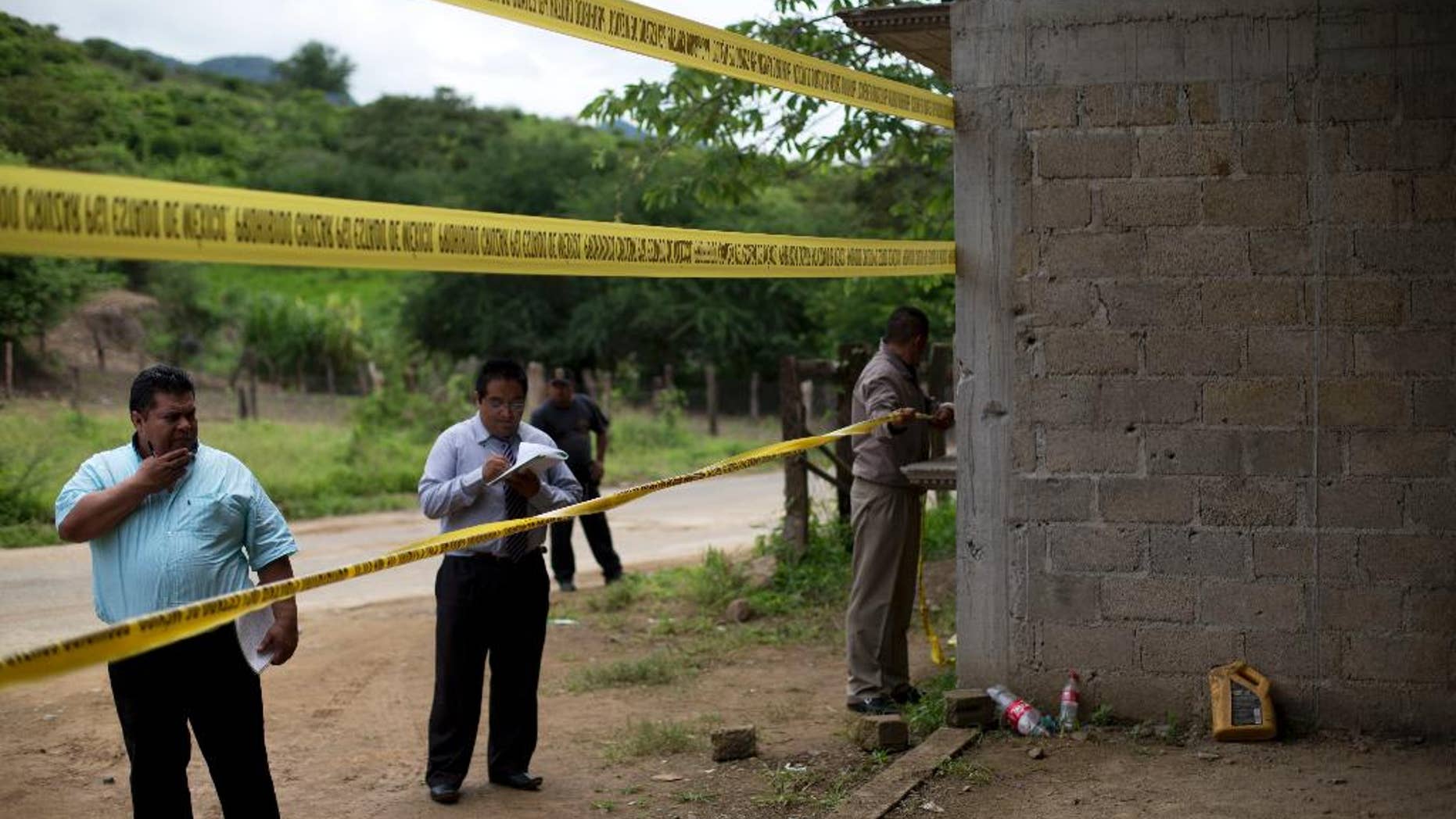 FILE - In this July 3, 2014 file photo, state authorities seal off an unfinished grain warehouse that was the site of a shootout between soldiers and alleged criminals on the outskirts of the village of San Pedro Limon in Mexico state, Mexico. Authorities in Mexico said Tuesday, July 19, 2016 they will fire seven or eight investigators and suspend 22 others for misconduct related to the 2014 army slayings of 22 suspected gang members. The country's human rights commission says soldiers killed at least a dozen of the suspects after they surrendered. (AP Photo/Rebecca Blackwell, File)