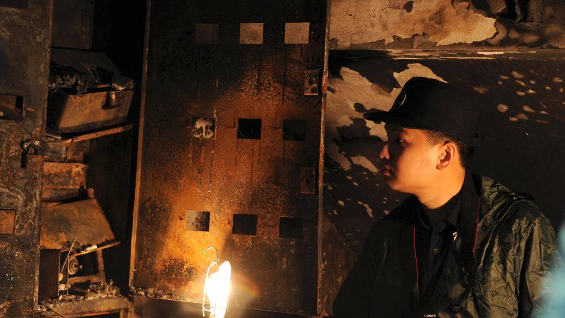 In this photo released by China's Xinhua News Agency, a man checks a charred ammeter box at a seven-story apartment building after a fire in Zhengzhou, capital of central China's Henan Province, Thursday, June 25, 2015. A fire erupted on the ground level of the building in the early morning but the cause of the fire was not known, state broadcaster CCTV said. (Zhu Xiang/Xinhua via AP) NO SALES