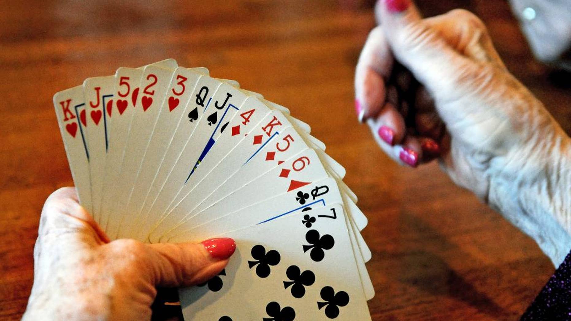 FILE - In this April 10, 2014, file photo, a card player studies her hand during a bridge game at a restaurant in St. Paul, Minn. Research published on Monday, Jan. 30, 2017, shows that even in one's 70s and beyond, simple activities including web-surfing, playing bridge and socializing can stave off mental decline. (Jean Pieri/Pioneer Press via AP)