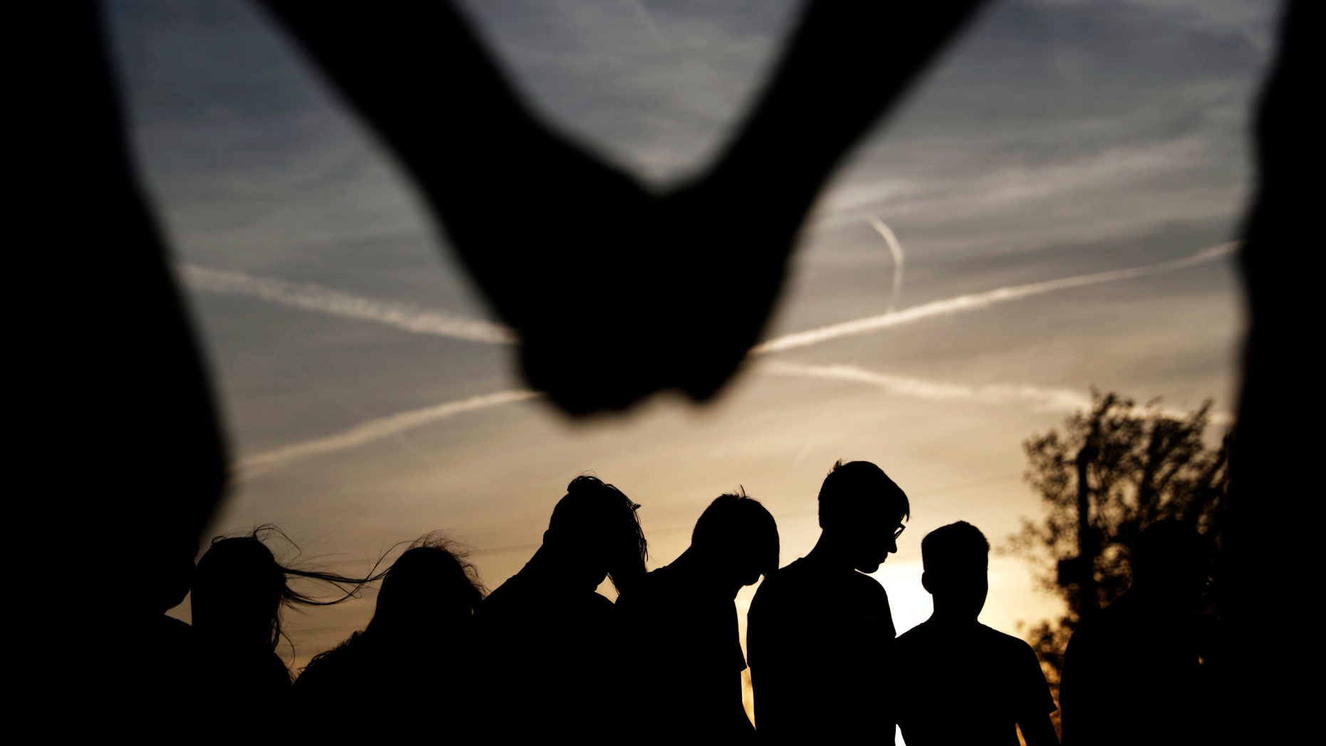 In this Sunday April 10, 2016 photo, youths hold hands for a prayer during a gathering at sunset outside the Christian Fellowship Church in Benton, Ky. Nearly a quarter of Americans say they no longer affiliate with a faith tradition. It's the highest share ever recorded in surveys, indicating the stigma for not being religious has eased, even in heavily evangelical areas. Americans who say they have no ties to organized religion, dubbed "nones," now make up about 23 percent of the population, just behind evangelicals, who comprise about 25 percent, according to the Pew Research Center. (AP Photo/David Goldman)
