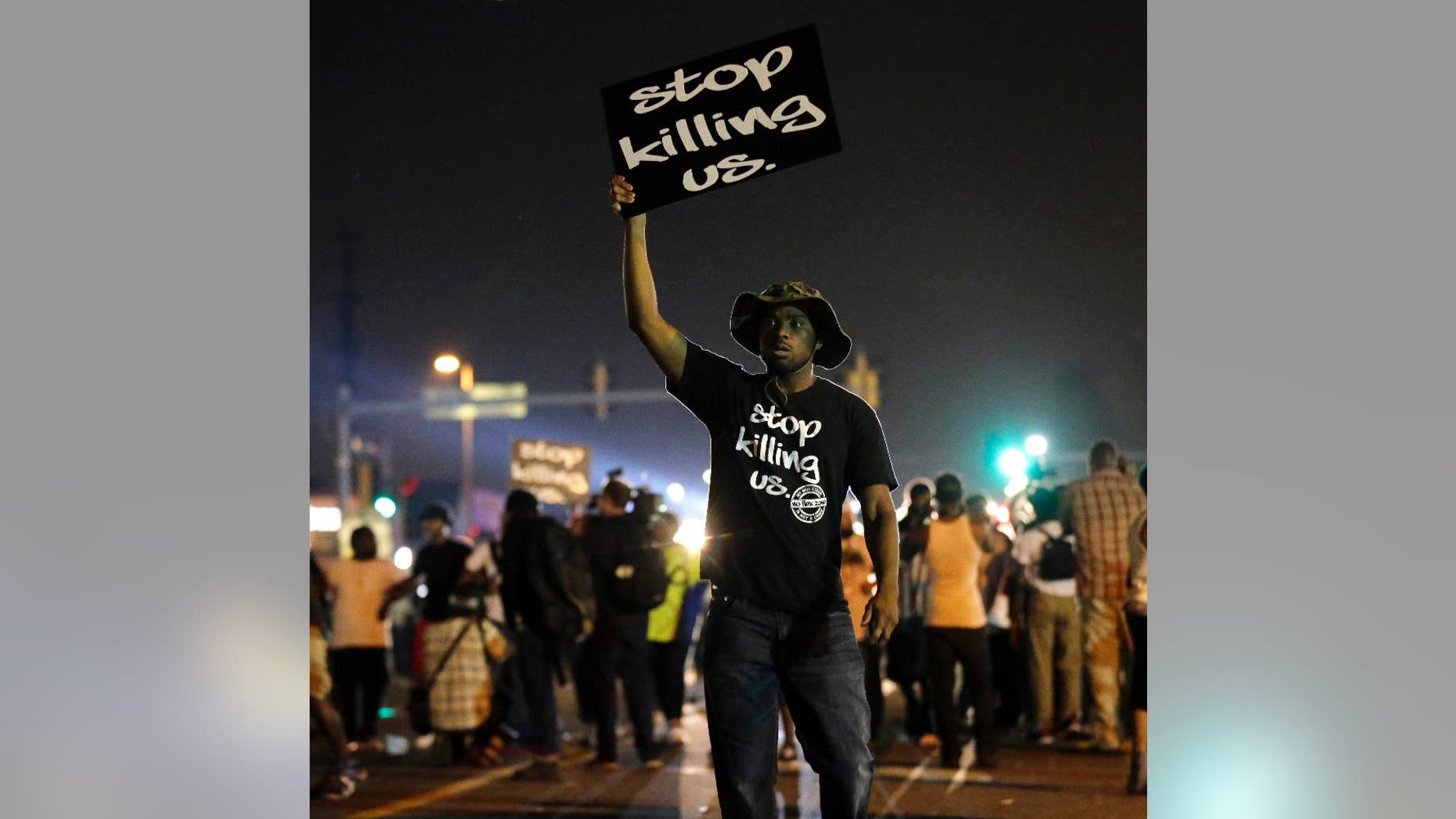 FILE - In this Aug. 18, 2014, file photo, protesters walk through the streets after a standoff with police in Ferguson, Mo. A year ago, most Americans had never heard of the St. Louis suburb called Ferguson. But after a white police officer fatally shot a black 18-year-old in the street, the name of the middle-class community quickly became known around the world. (AP Photo/Charlie Riedel, File)