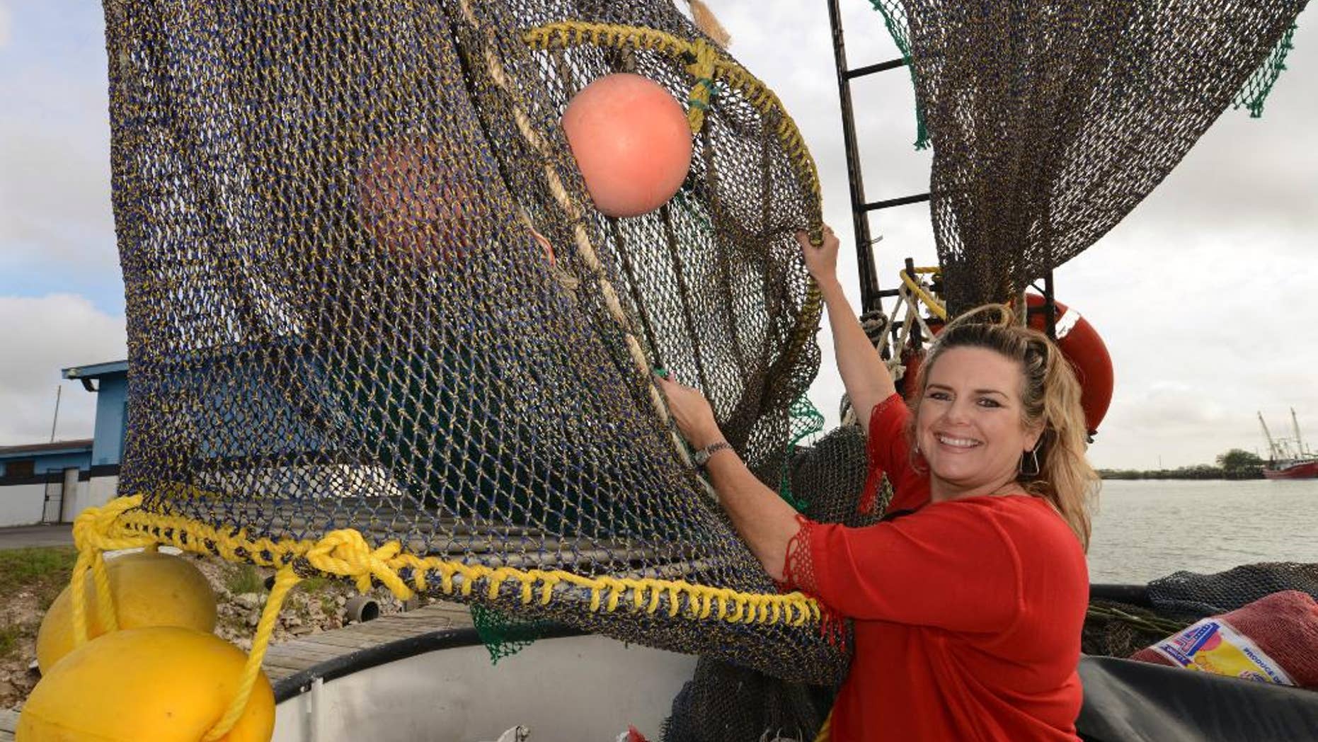 FILE - In this Friday, Dec. 5, 2014 file photo, Andrea Hance, Texas Shrimp Association executive director, poses with a TED, or turtle excluder device, on board a shrimp boat at the Brownsville Shrimp Basin in Brownsville, Texas. Under proposed new federal rules released on Thursday, Dec. 15, 2016, more shrimp fishermen would have to use nets equipped with turtle escape hatches, to prevent sea turtle deaths. (Brad Doherty/The Brownsville Herald via AP, File)