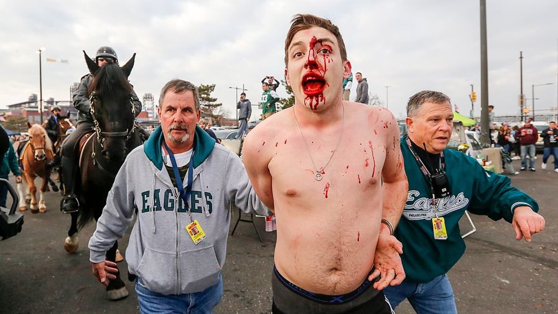 A bloodied fan was arrested by police after a massive fight broke out between Eagles tailgating fans and cops hours before the NFC Championship game with the Minnesota Vikings. (Andrew Mills/NJ Advance Media via AP)