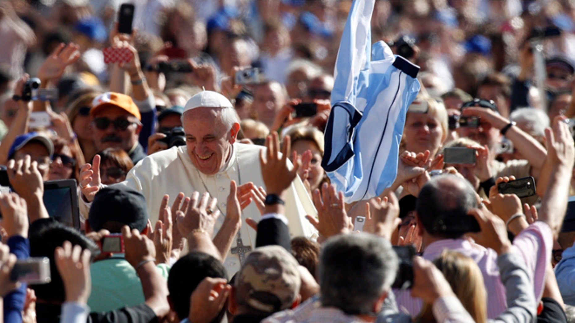 A faithful tosses in the air a jersey with the colors of the Argentine flag as Pope Francis greets faithful upon arrival for his weekly general audience in St. Peter's Square at the Vatican, Wednesday, Sept. 18, 2013. (AP Photo/Riccardo De Luca)