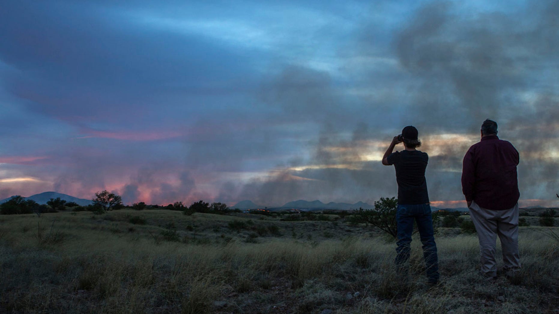 In this Monday, April 24, 2017 photo, people watch the Sawmill Fire from Las Cienegas Conservation Area north of Sonoita, Ariz.