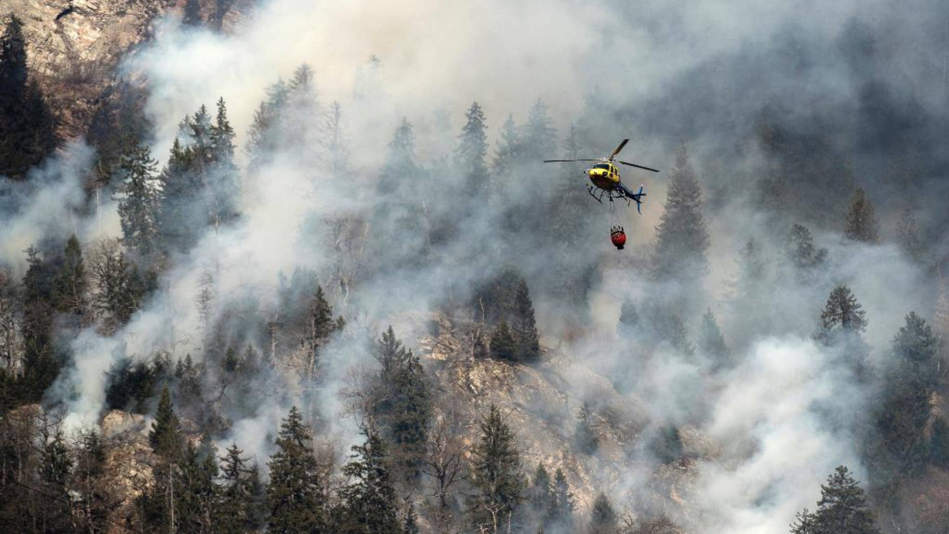 A fire fighting helicopter discharges water over the forest fires near Mesocco in Southern Switzerland, Wednesday, Dec. 28, 2016. (Gabriele Putzu/Keystone,Ti-Press via AP)
