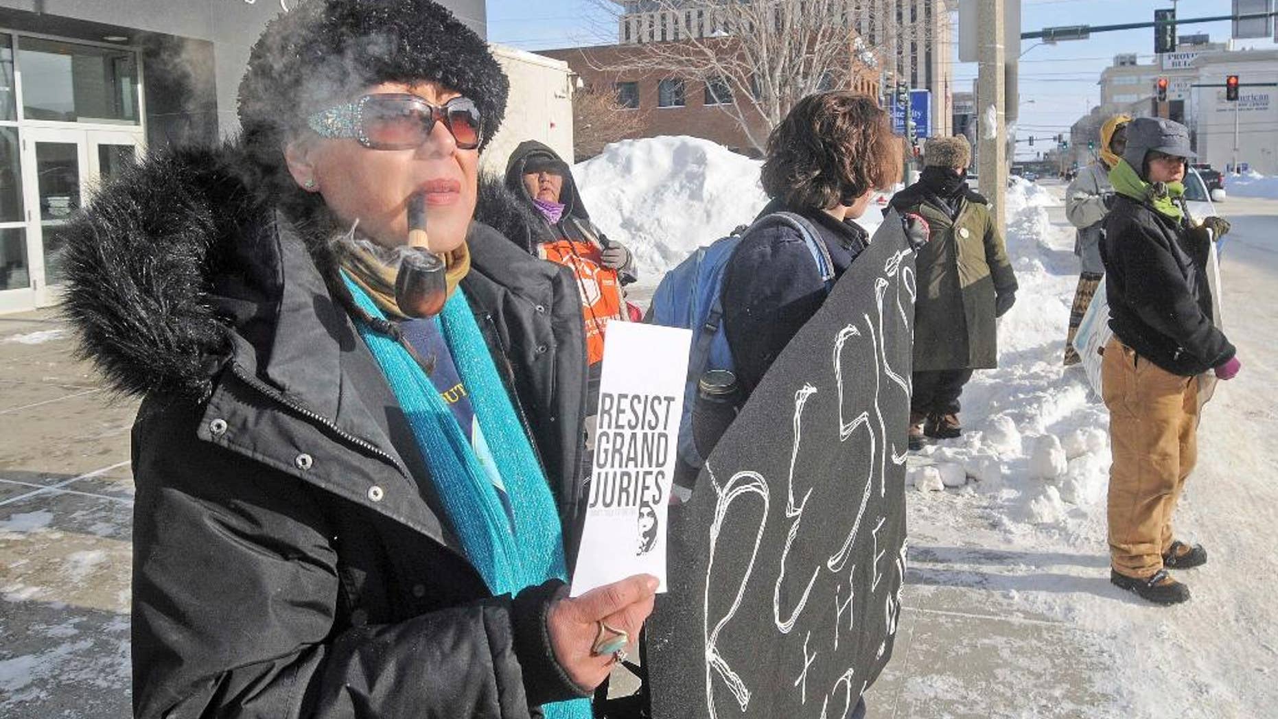 Vivian Billy, left, was outside the Federal Building in downtown Bismarck on Wednesday, Jan. 4, 2017, handing out resist grand jury pamphlets while helping hold a banner with other protesters against the Dakota Access Pipeline. (Tom Stromme/The Bismarck Tribune via AP)