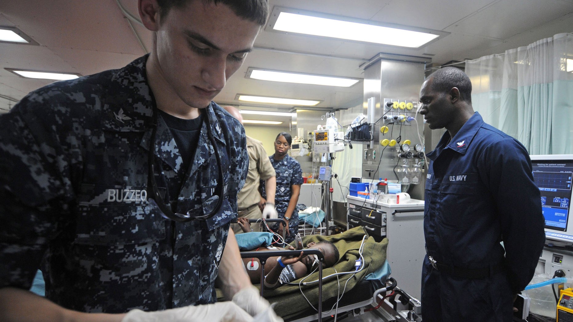 ATLANTIC OCEAN - JANUARY 19: (IMAGE RELEASED BY U.S. MILITARY) In this handout image provided by the U.S. Na, Hospital Corpsman 3rd Class Adam Buzzeo prepares medical equipment during the assessment of a six-year-old Haitian boy brought aboard the Military Sealift Command hospital ship USNS Comfort (T-AH 20) on January 19, 2010. The boy, who was Comfort's first patient as part of Operation Unified Response, suffered an injury to his bladder and a hip fracture during an earthquake that struck Haiti on January 12, 2010. The boy is in the intensive care unit aboard Comfort in stable condition. Comfort is supporting Operation Unified Response, a joint operation providing humanitarian assistance to Haiti. (Photo by U.S. Navy/Petty Officer 2nd Class Chelsea Kennedy via Getty Images)