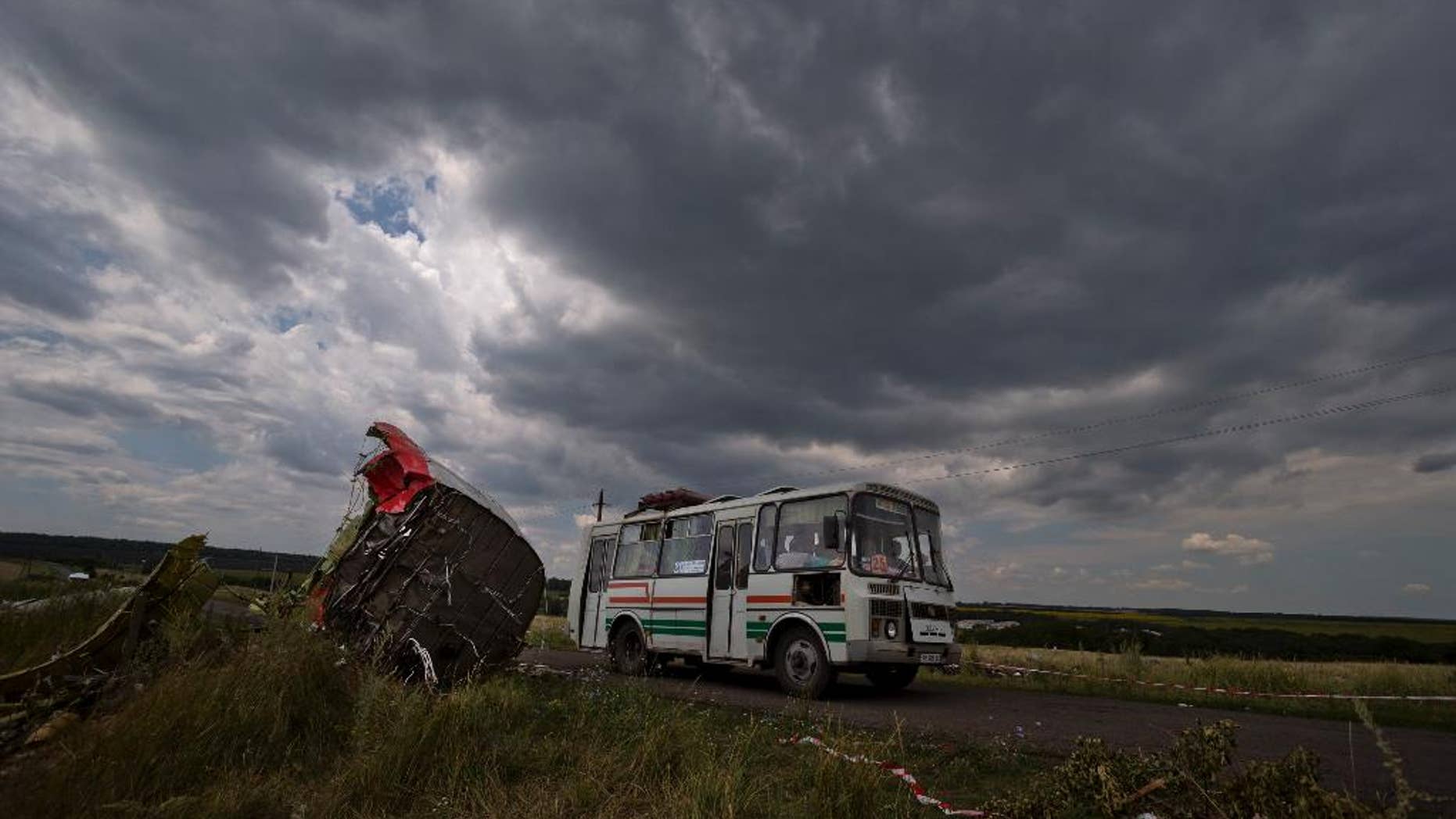 A commuter bus drives by aircraft wreckage at the crash site of Malaysia Airlines Flight 17 near the village of Hrabove, eastern Ukraine, Tuesday, July 22, 2014. A team of Malaysian investigators visited the site along with members of the OSCE mission in Ukraine for the first time since the air crash last week.(AP Photo/Vadim Ghirda)