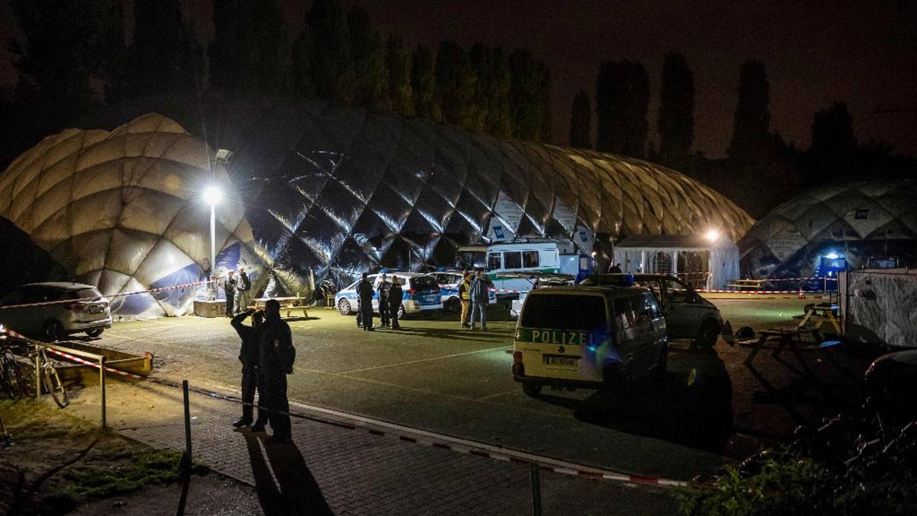 Police officers stand in front of an air-inflated structure which is a shelter for refugees in Berlin, Wednesday morning, Sept. 28, 2016. A 29-years-old man has been killed by police after a knife attack. (Gregor Fischer/dpa via AP)