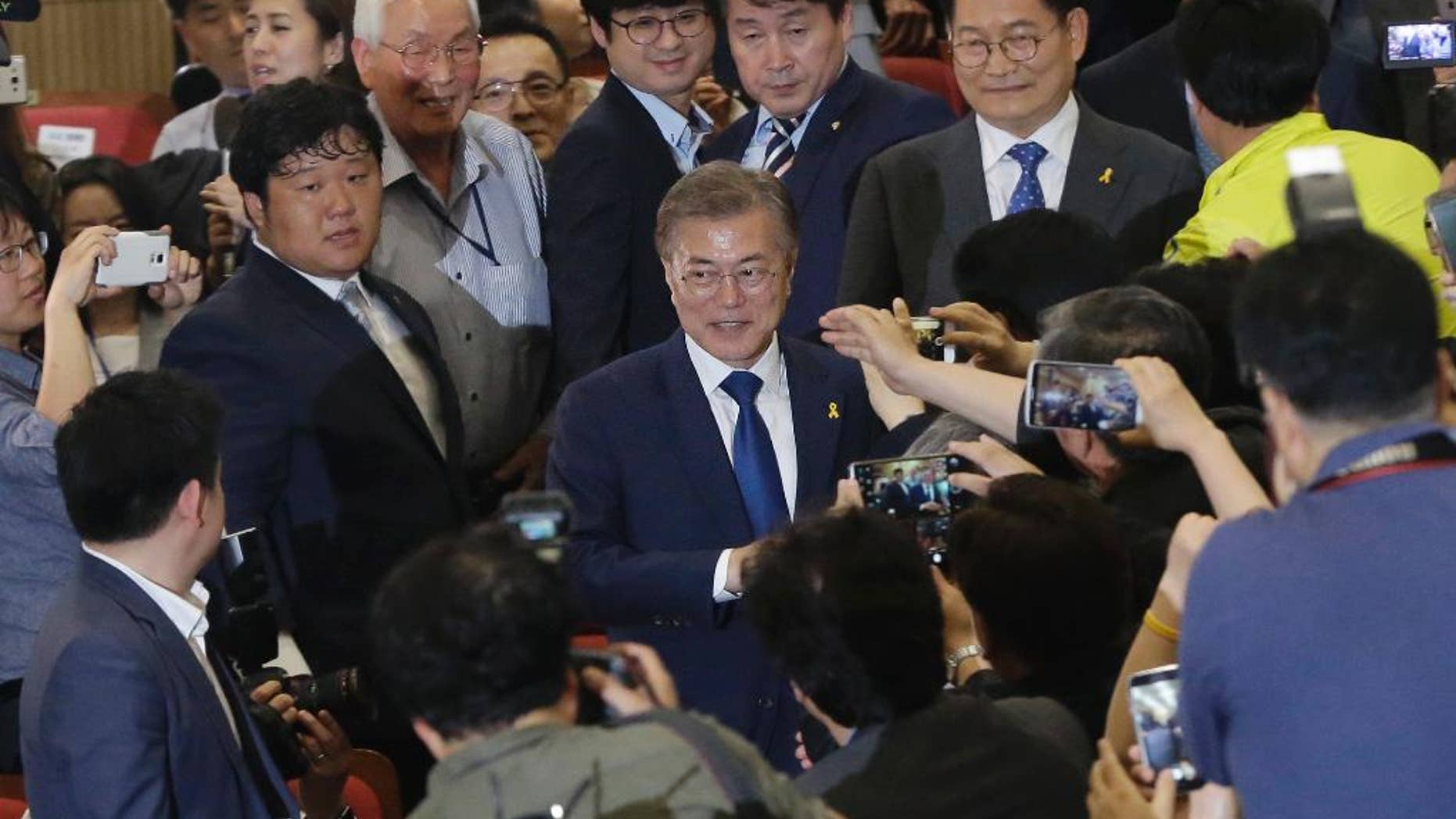 South Korea's presidential candidate Moon Jae-in, center, of the Democratic Party is celebrated by his party leaders and members as they watch the local media's results of exit polls for the presidential election on television in Seoul, South Korea, Tuesday, May 9, 2017. Exit polls forecast that liberal candidate Moon will win the election Tuesday to succeed ousted President Park Geun-hye. (AP Photo/Ahn Young-joon)