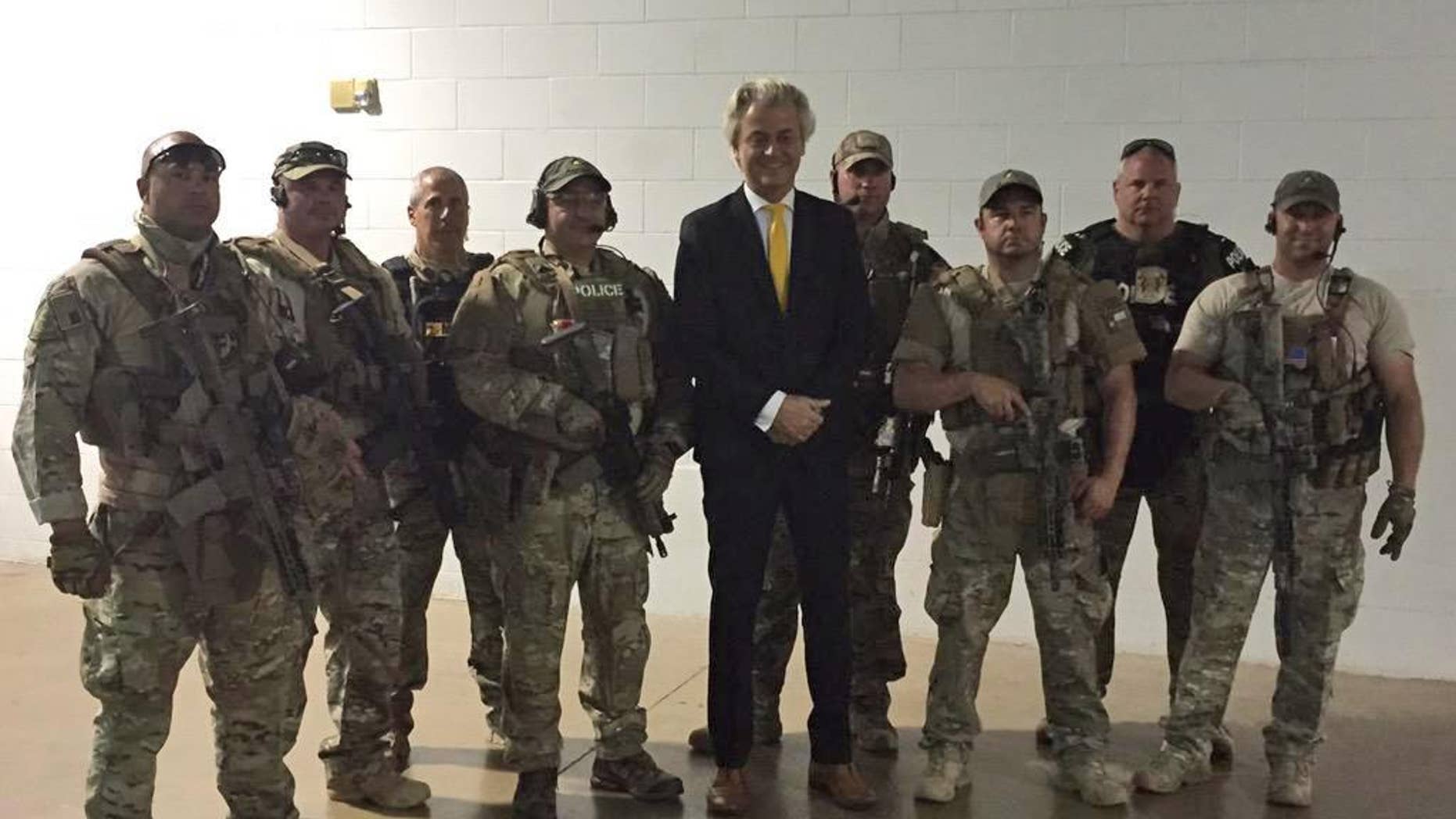 In this photo provided on Monday, May 4, 2015 by Geert Wilders, Dutch lawmaker Geert Wilders, leader of the anti-Islam Freedom Party, center, poses for a photograph with police officers who responded to a shooting outside a provocative contest for cartoon depictions of Prophet Muhammad in Garland, Texas. Two gunmen were killed Sunday, May 3, 2015 in Texas after opening fire on a security officer outside a provocative contest for cartoon depictions of Prophet Muhammad, and a bomb squad was called in to search their vehicle as a precaution, authorities said. (Geert Wilders via AP)