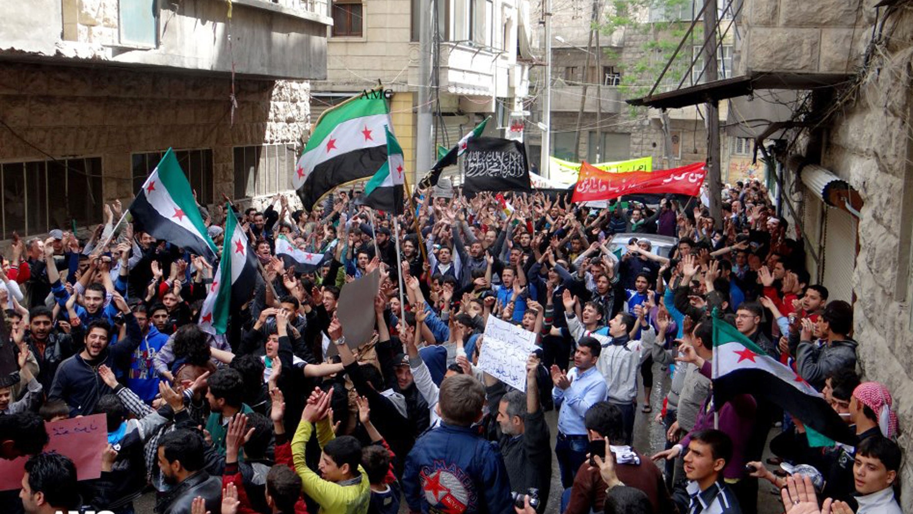 This citizen journalism image provided by Aleppo Media Center AMC which has been authenticated based on its contents and other AP reporting, shows anti Syrian regime protesters chanting slogans and waving the Syrian revolutionary flag during a demonstration, in Aleppo, Syria, Friday, April 19, 2013. Gunmen killed a government official in a Damascus restaurant, Syrian state media and activists reported Friday as regime troops and rebels fought fierce battles near the Lebanese border.(AP Photo/Aleppo Media Center, AMC)