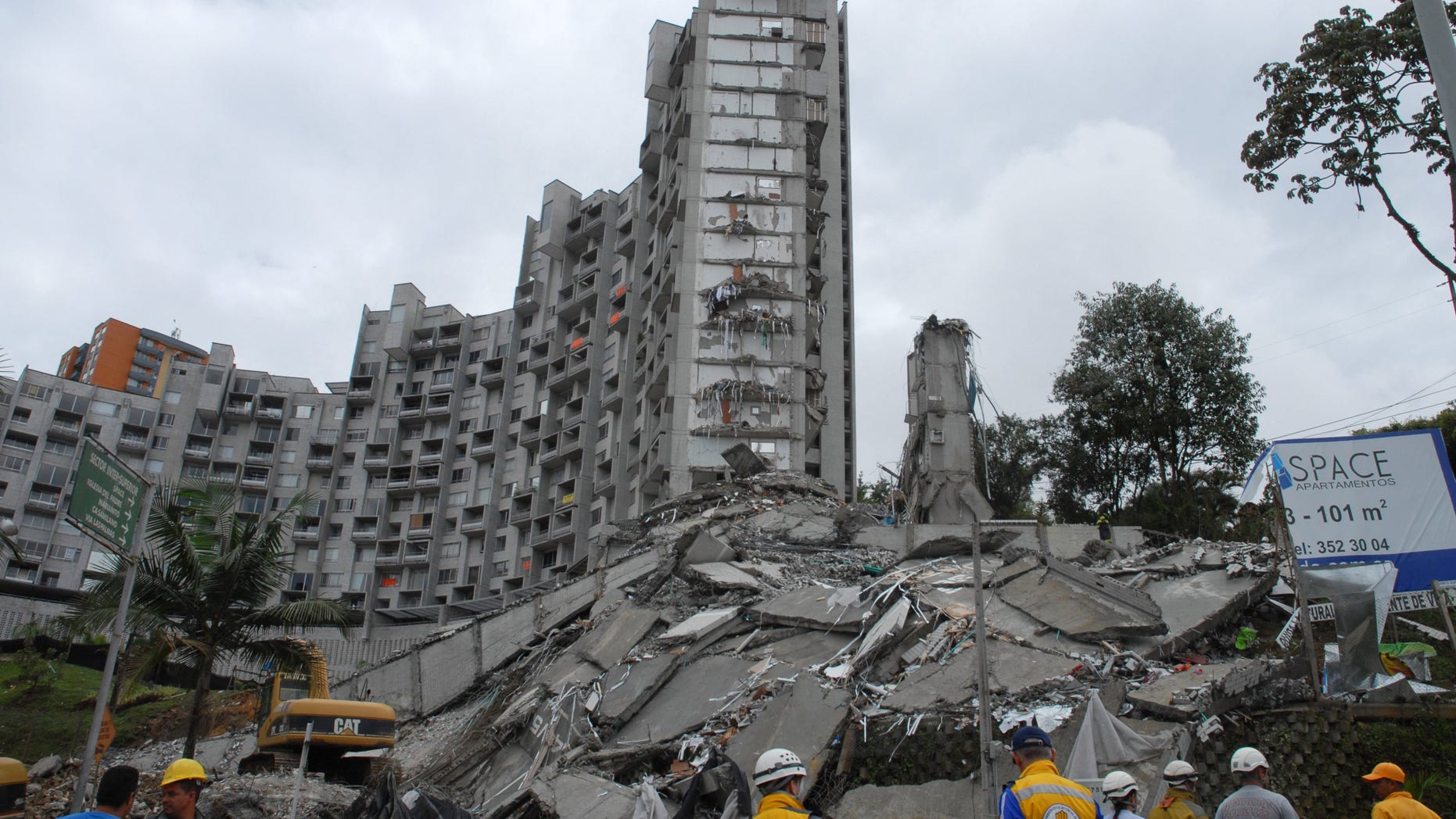 Rescue workers look at the remains of a building that collapsed late Saturday, in Medellin, Colombia, on Sunday, Oct. 13, 2013. Medellin disaster preparedness chief Jaime Enrique Gomez says they're trying to rescue 11 people missing in the collapse of a high-rise building and they still hold out hope of finding all alive following the Saturday night collapse in one of the most exclusive neighborhoods of Medellin, Colombia's second-largest city. (AP Photo/Luis Benavides)