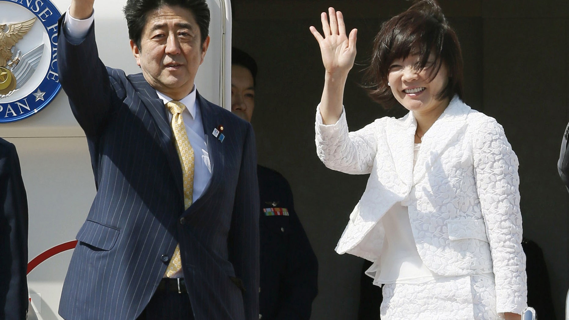 Japanese Prime Minister Shinzo Abe and his wife Akie wave before boarding a plane at Tokyo's Haneda Airport Friday, May 24, 2013. Abe is traveling to Myanmar for a three-day trip, the first visit to the country by a Japanese leader in 36 years. (AP Photo/Kyodo News) JAPAN OUT, MANDATORY CREDIT