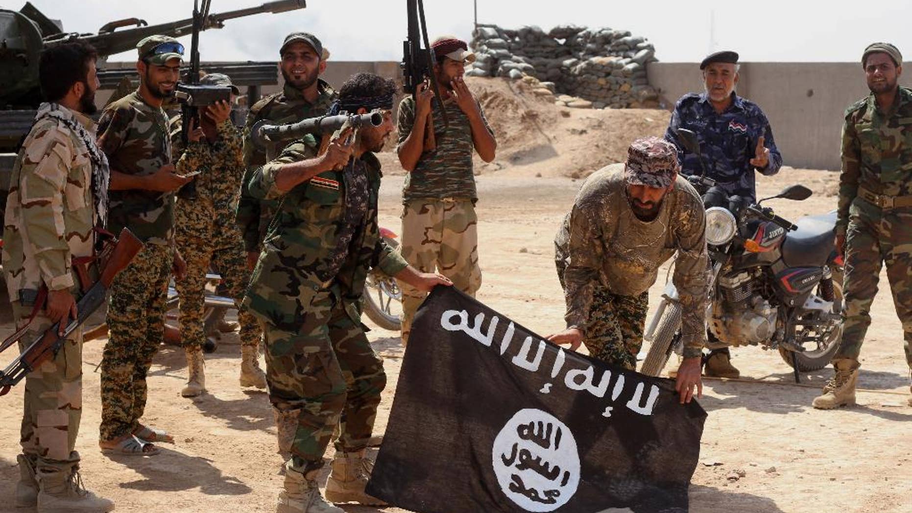 Sept. 1, 2014: Iraqi security forces hold a flag of the Islamic State group they captured during an operation outside Amirli, some 105 miles north of Baghdad, Iraq. (AP)