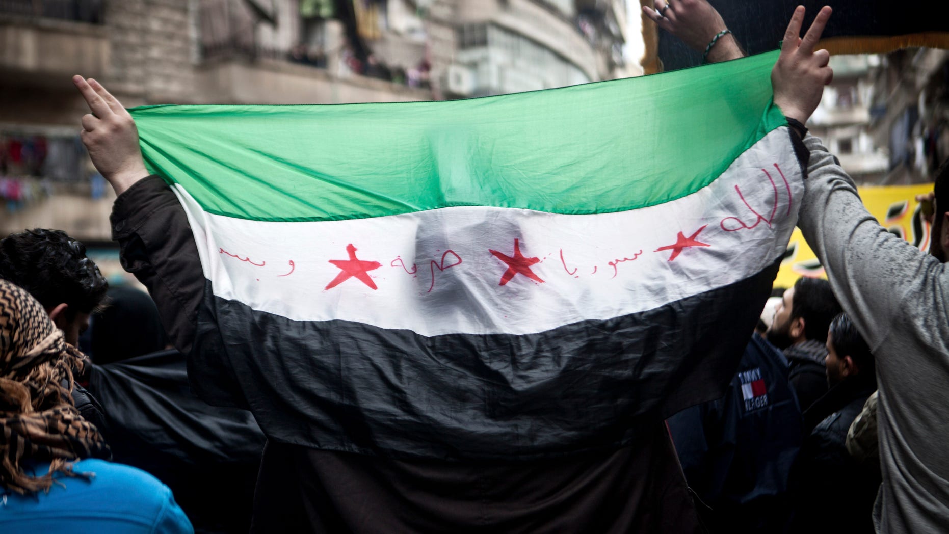 A Syrian carries a revolution flag during a Friday protest in Aleppo, Syria, where young people and children sang songs against Bashar Assad and the Syrian regime, Friday, Dec. 21, 2012.(AP Photo/Virginie Nguyen Hoang)