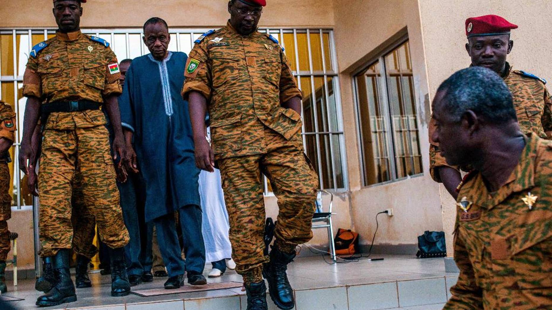 Burkina Faso Lt. Col. Issac Yacouba Zida, center, leaves a government building after meeting with political leaders in Ouagadougou, Burkina Faso, Tuesday, Nov. 4, 2014. International envoys tried Tuesday to resolve Burkina Faso's political crisis, with the specter of a power vacuum looming after the country's longtime president fled last week. (AP Photo/Theo Renaut)