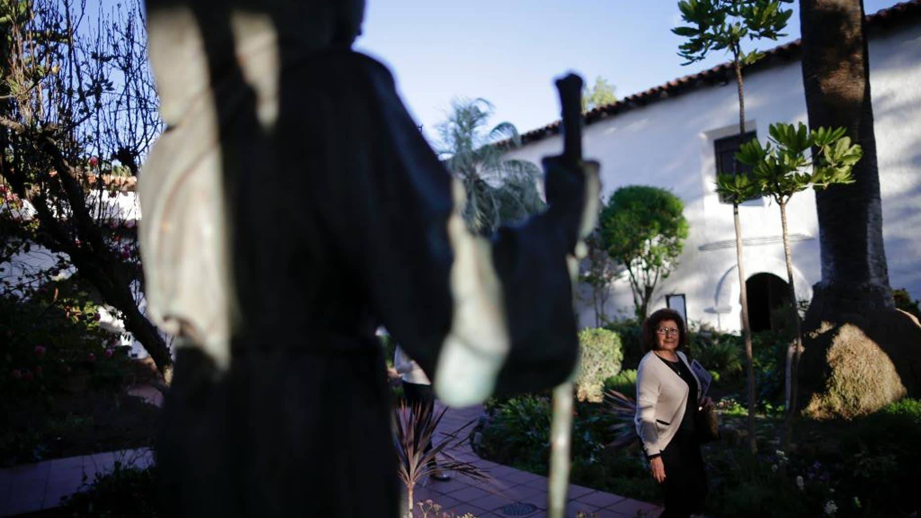 FILE - In this Jan. 27, 2015 file photo, a woman passes a statue of Franciscan missionary Junipero Serra at the Mission San Diego de Acala in San Diego. Pope Francis’ apology for the Roman Catholic Church’s crimes against indigenous peoples has not softened opposition among some California Native Americans to his decision to canonize 18th-century Franciscan missionary Junipero Serra, extolled by the Vatican as a great evangelizer, but denounced by some tribal officials as a destroyer of Native culture. (AP Photo/Gregory Bull, File)