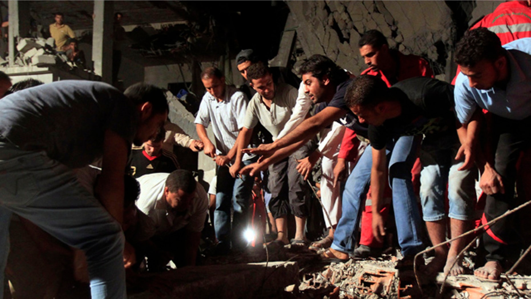 June 19: In this photo taken on a government-organized tour, Libyan firefighters and local residents remove debris from a damaged residential building.
