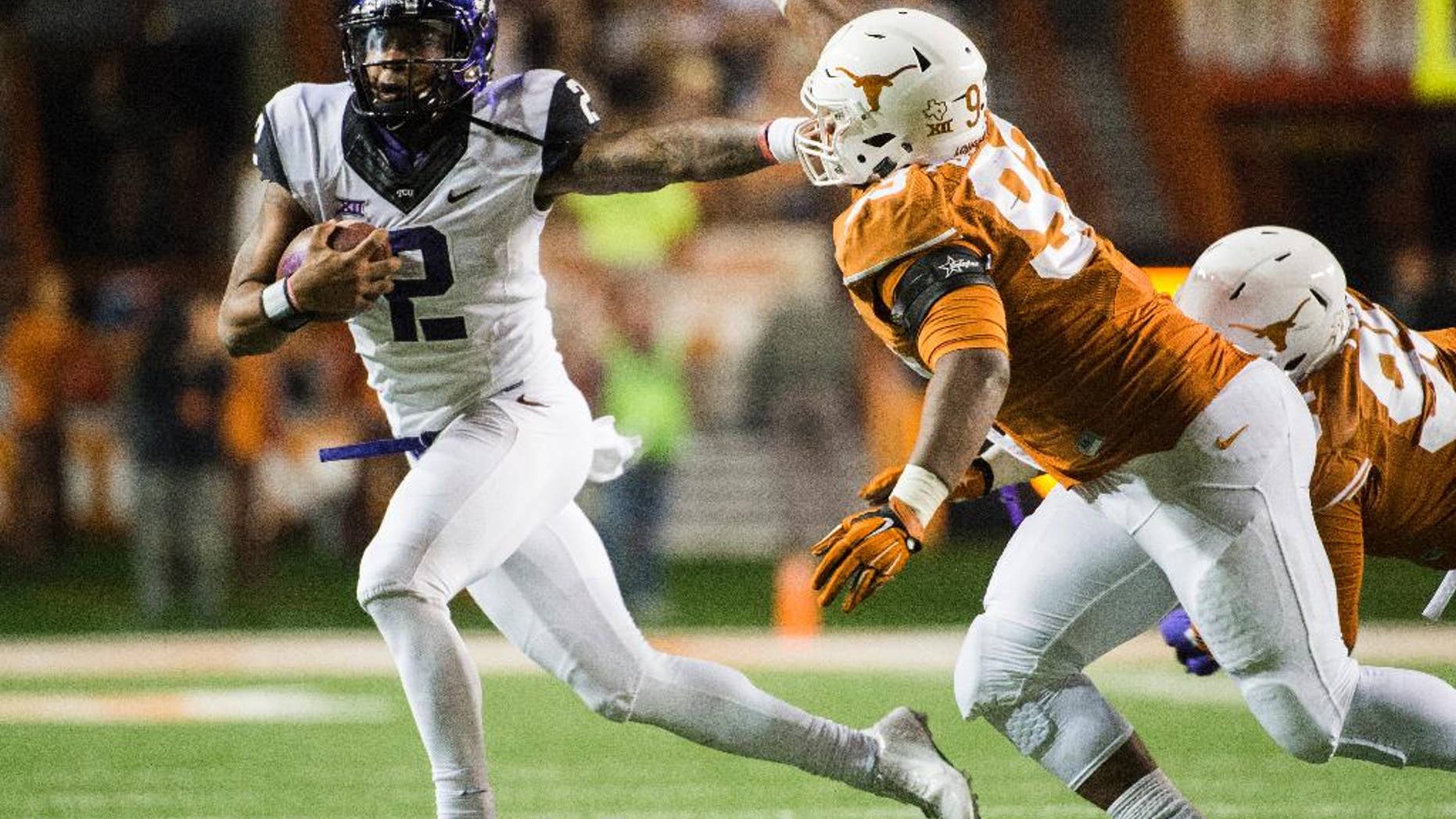 CORRECTS NAME OF TCU PLAYER TO TREVONE BOYKIN - TCU's Trevone Boykin (2) holds off Texas' Paul Boyette Jr. (93) during the second half of an NCAA college football game, Thursday, Nov. 27, 2014, in Austin, Texas. (AP Photo/Ashley Landis)