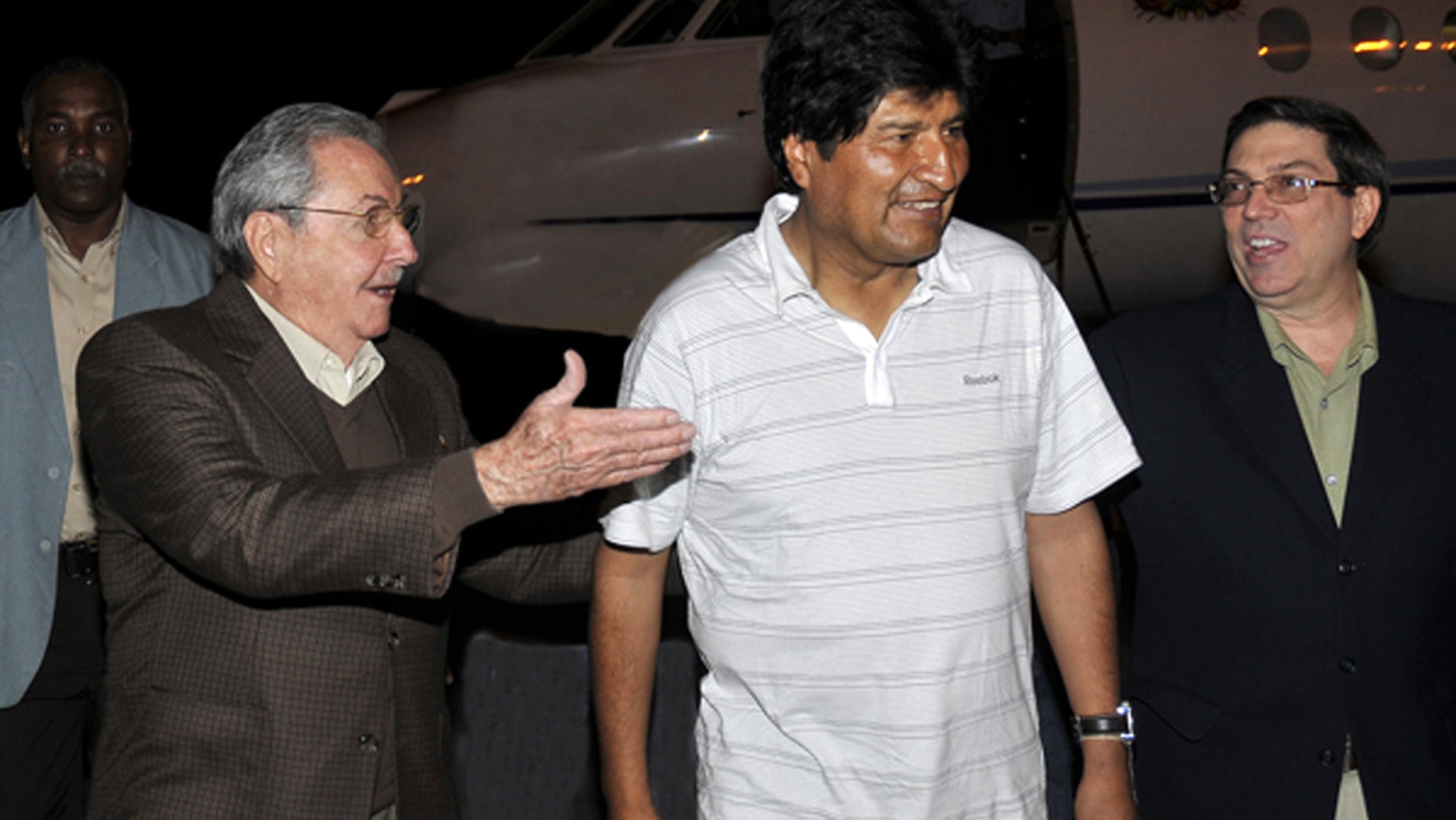 In this picture released by the Cuban newspaper Juventud Revelde, Bolivia's President Evo Morales, center, is welcomed by Cuba's President Raul Castro, left, and Cuba's Foreign Minister Bruno Rodriguez at the Jose Marti international airport in Havana, Cuba, early Sunday, Dec. 23, 2012. Evo Morales is in Cuba to visit Venezuela's President Hugo Chavez, who is recovering from a surgery, his fourth operation related to his pelvic cancer since June 2011. (AP Photo/Juventud Revelde, Estudios Revolucion)
