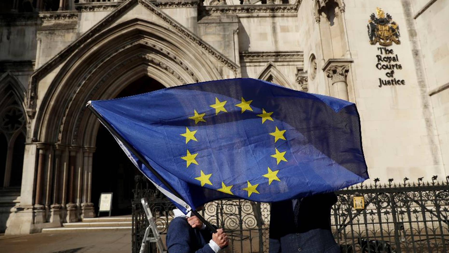Pro-EU membership supporter Phil Jones holds an EU flag outside the High Court, on the first day of the lawsuit of Gina Miller, a founder of investment management group SCM Private, in London, Thursday, Oct. 13, 2016. Rival protesters have gathered outside the High Court in London, where lawyers are battling over whether the government has the power to trigger Britain's exit from the European Union without approval from Parliament. (AP Photo/Matt Dunham)