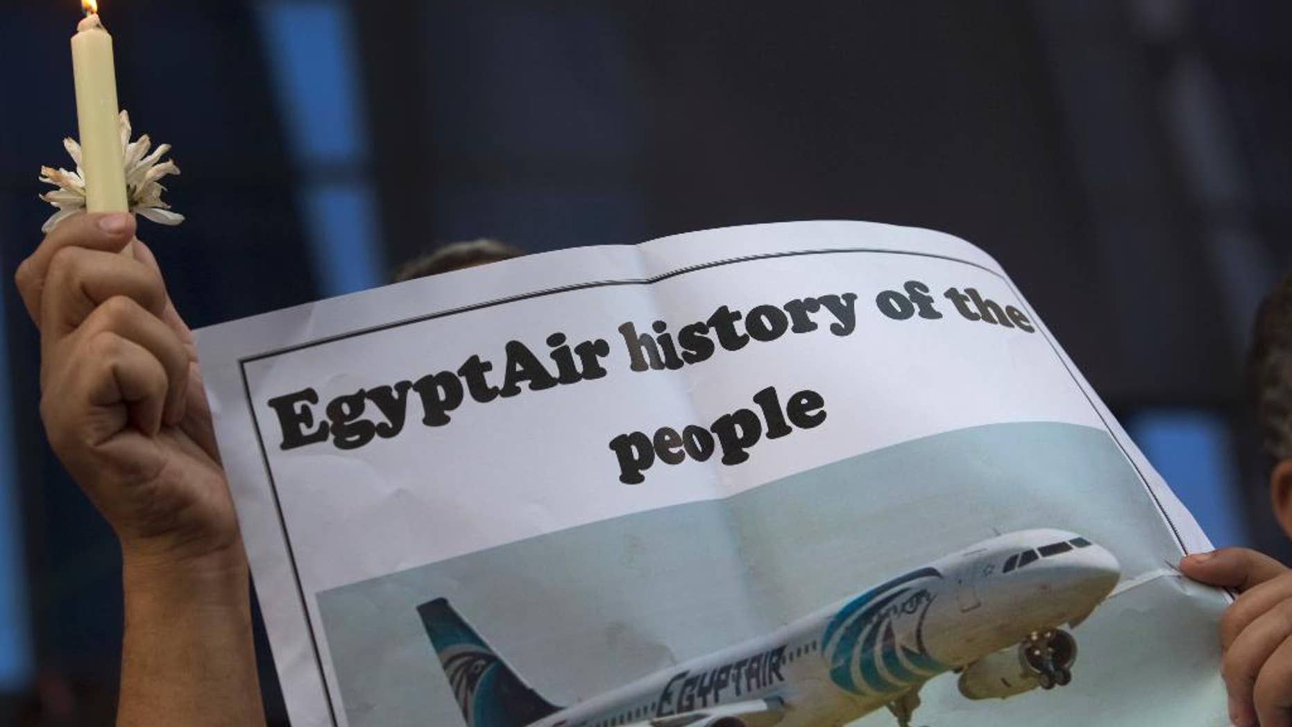 FILE - In this May 24, 2016 file photo, an Egyptian journalist holds a candle and a poster supporting EgyptAir during a candlelight vigil for the victims of EgyptAir flight 804 in front of the Journalists' Syndicate in Cairo, Egypt. Egypt on Wednesday, June 15, 2016, said that it spotted and obtained images from the wreckage of the EgyptAir plane flying from Paris to Cairo that crashed into the Mediterranean last month, killing all 66 people on board, according to a statement by the country's investigation committee. (AP Photo/Amr Nabil, File)