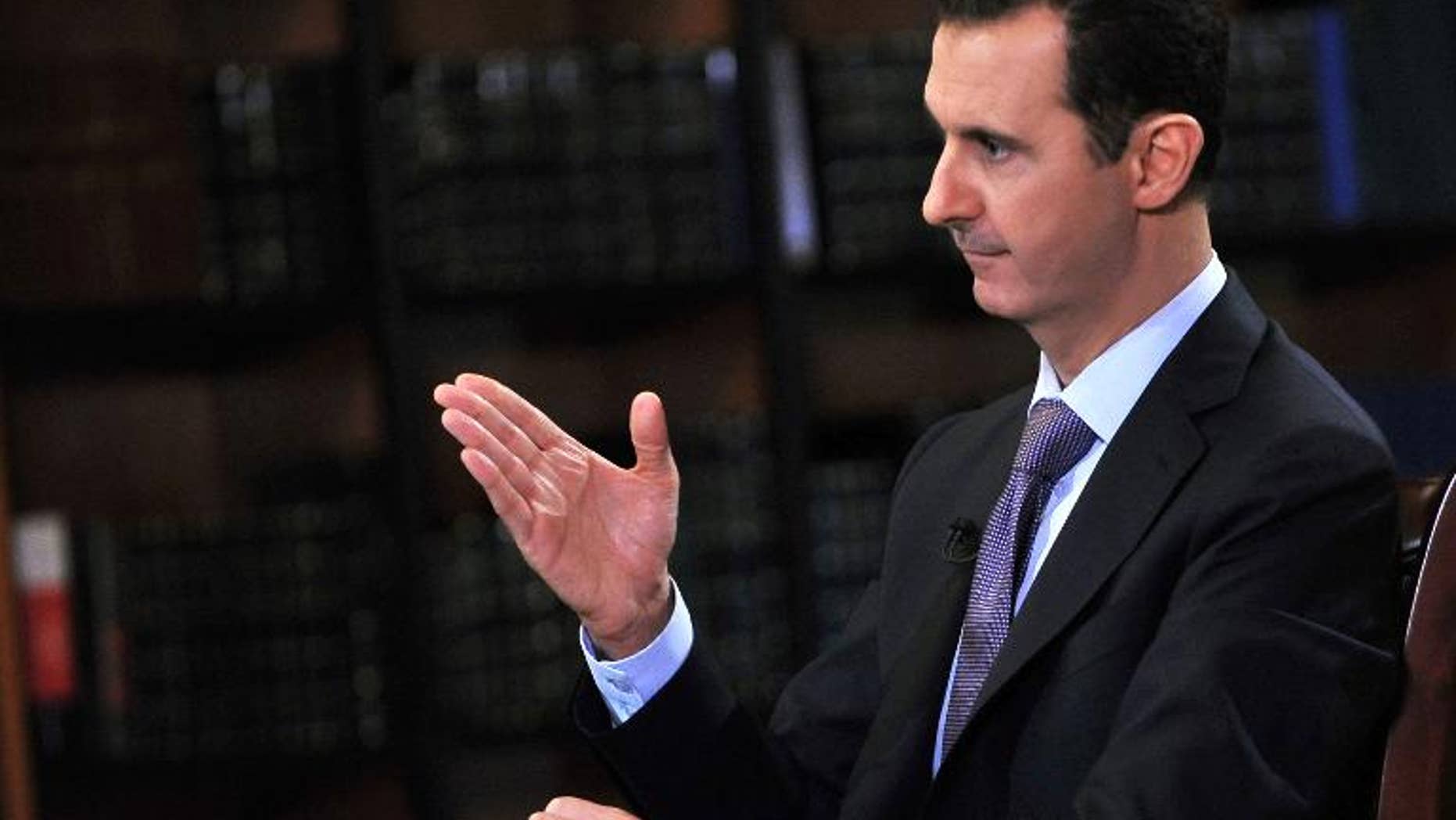 A handout picture released by SANA on September 29, 2013 shows President Bashar al-Assad gesturing during an interview with Italian television station Rai News 24 in Damascus